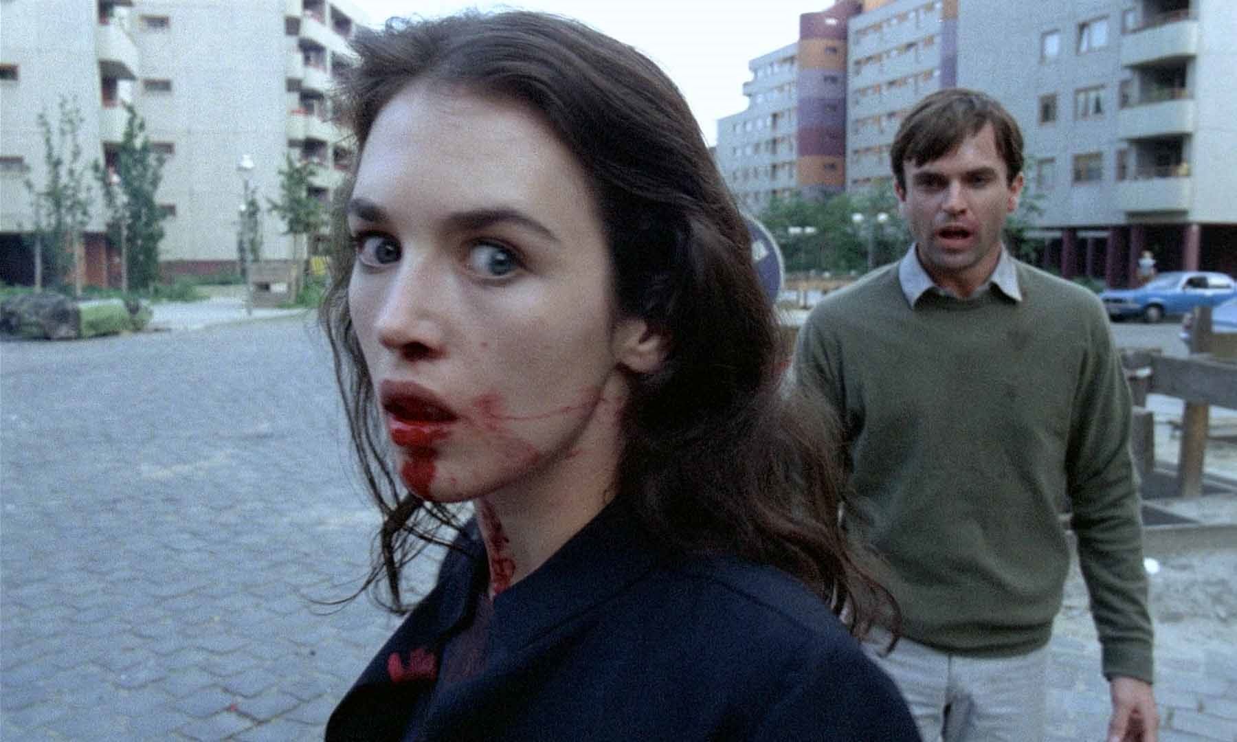 Isabelle Adjani with blood coming out of her mouth, and Sam Neill standing behind her, both looking distressed, in Possession.