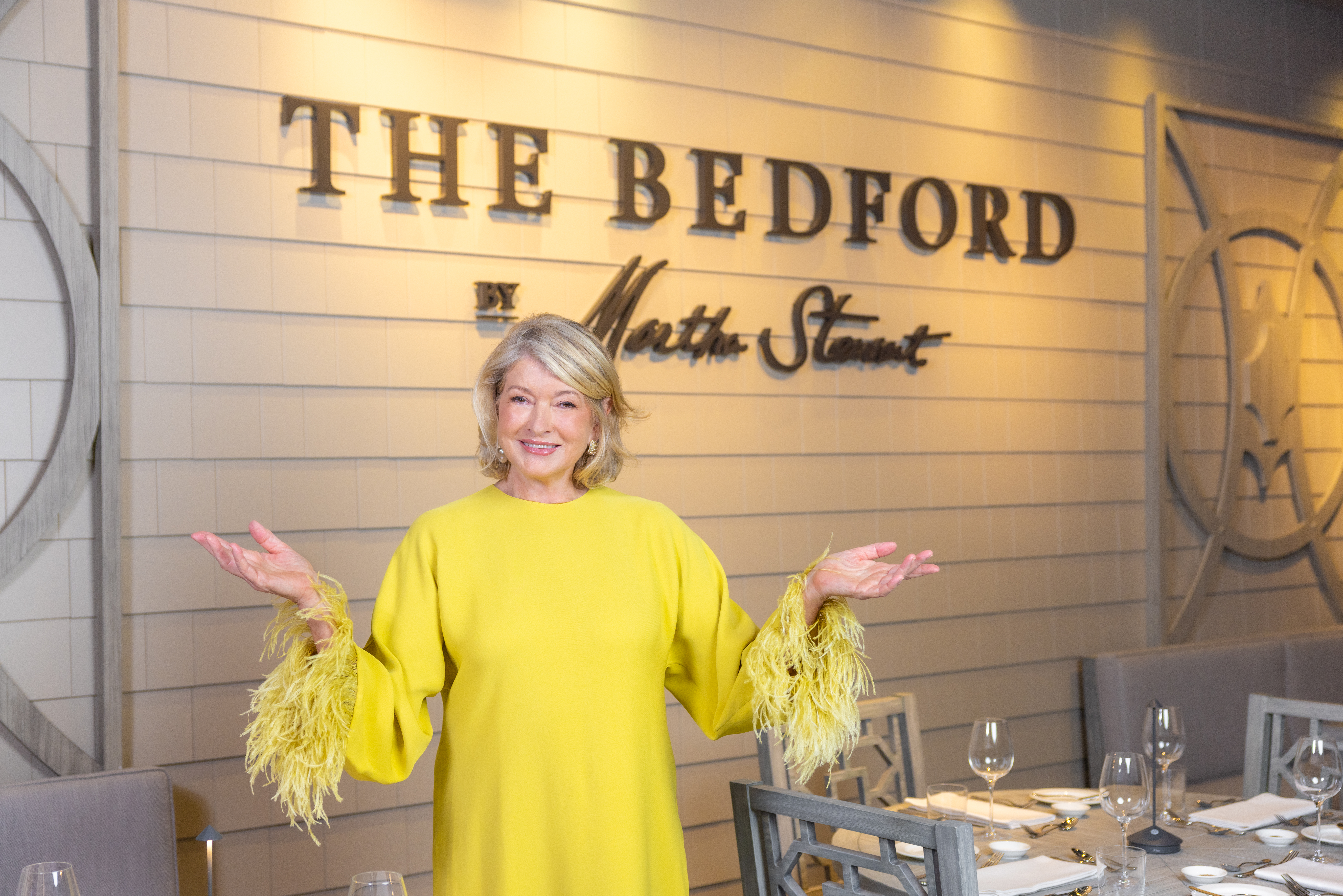 Martha Stewart standing in front of the sign at the Bedford