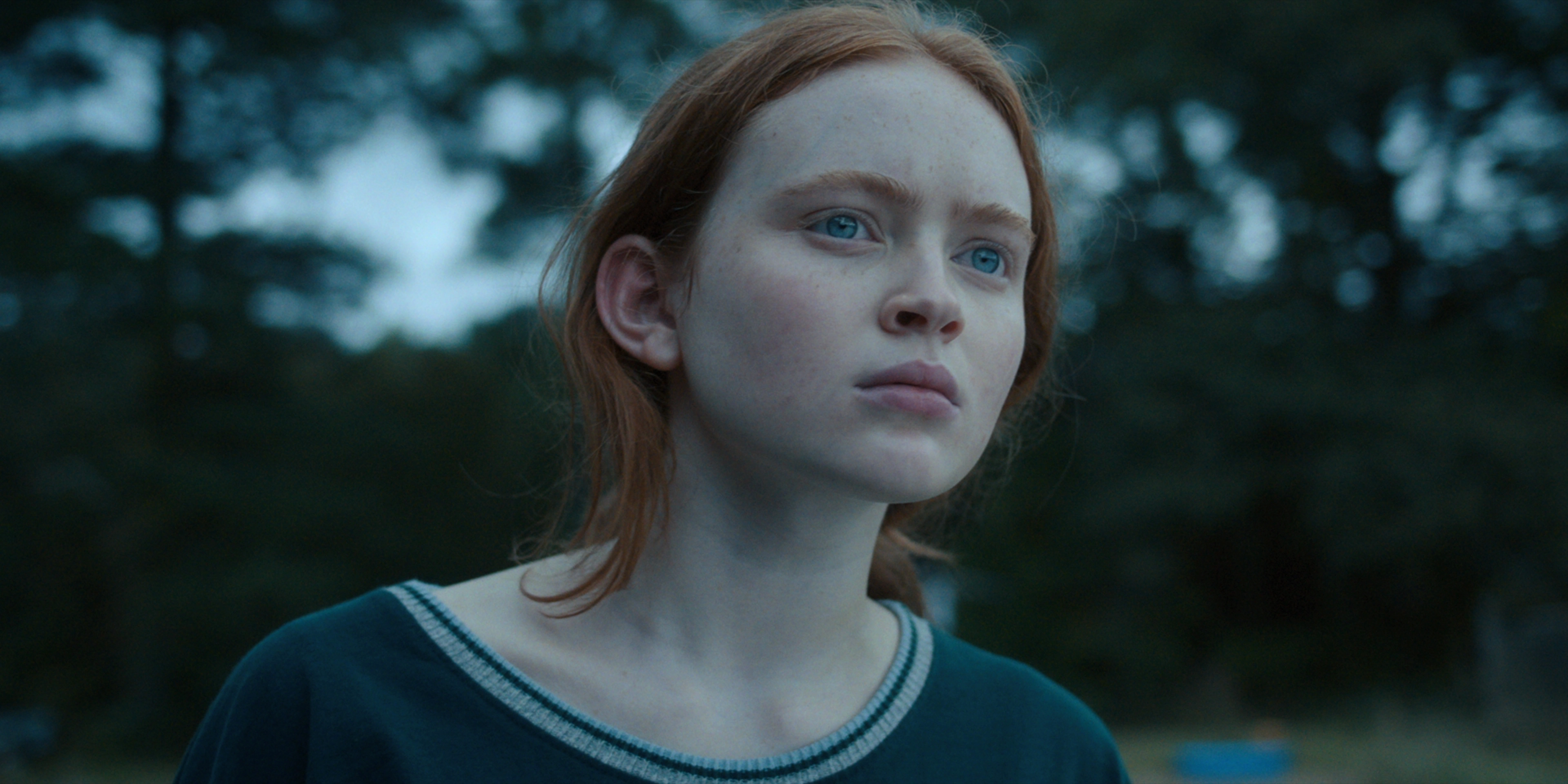 Stranger Things - Max Mayfield, portrayed by Sadie Sink. A pale young woman with red hair, she looks into the distance with a confused but intent expression.
