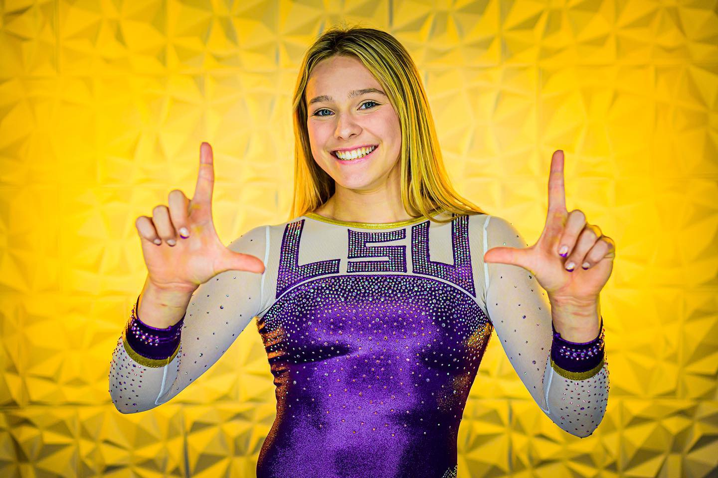 LSU gymnastics commit Lexi Zeiss posing with both hands in the shape of a capital letter “L”