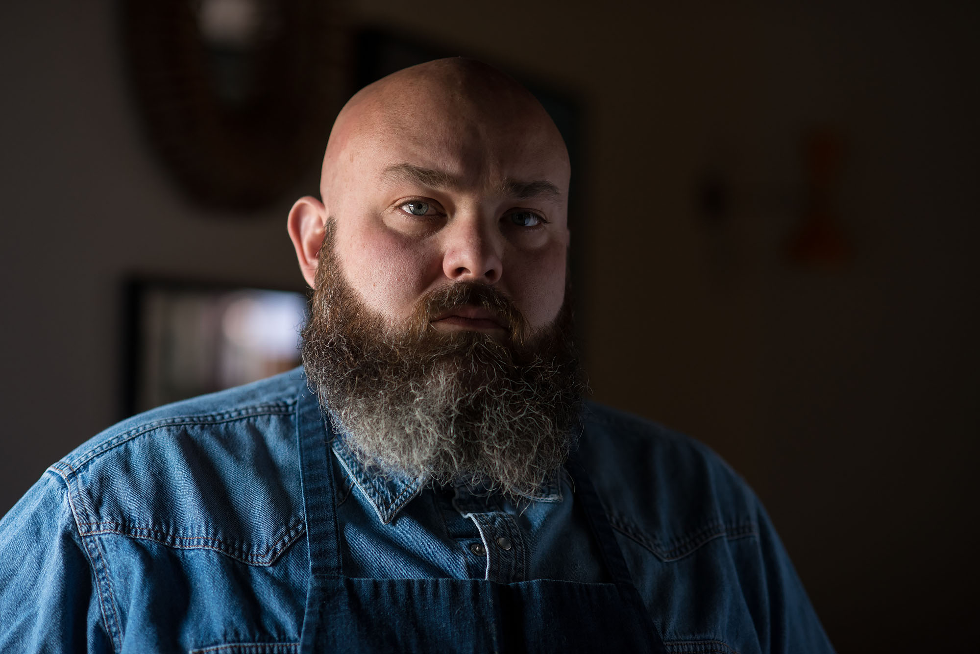 Chef Evan Funke stands looking at the camera with a large beard and stern eyes.