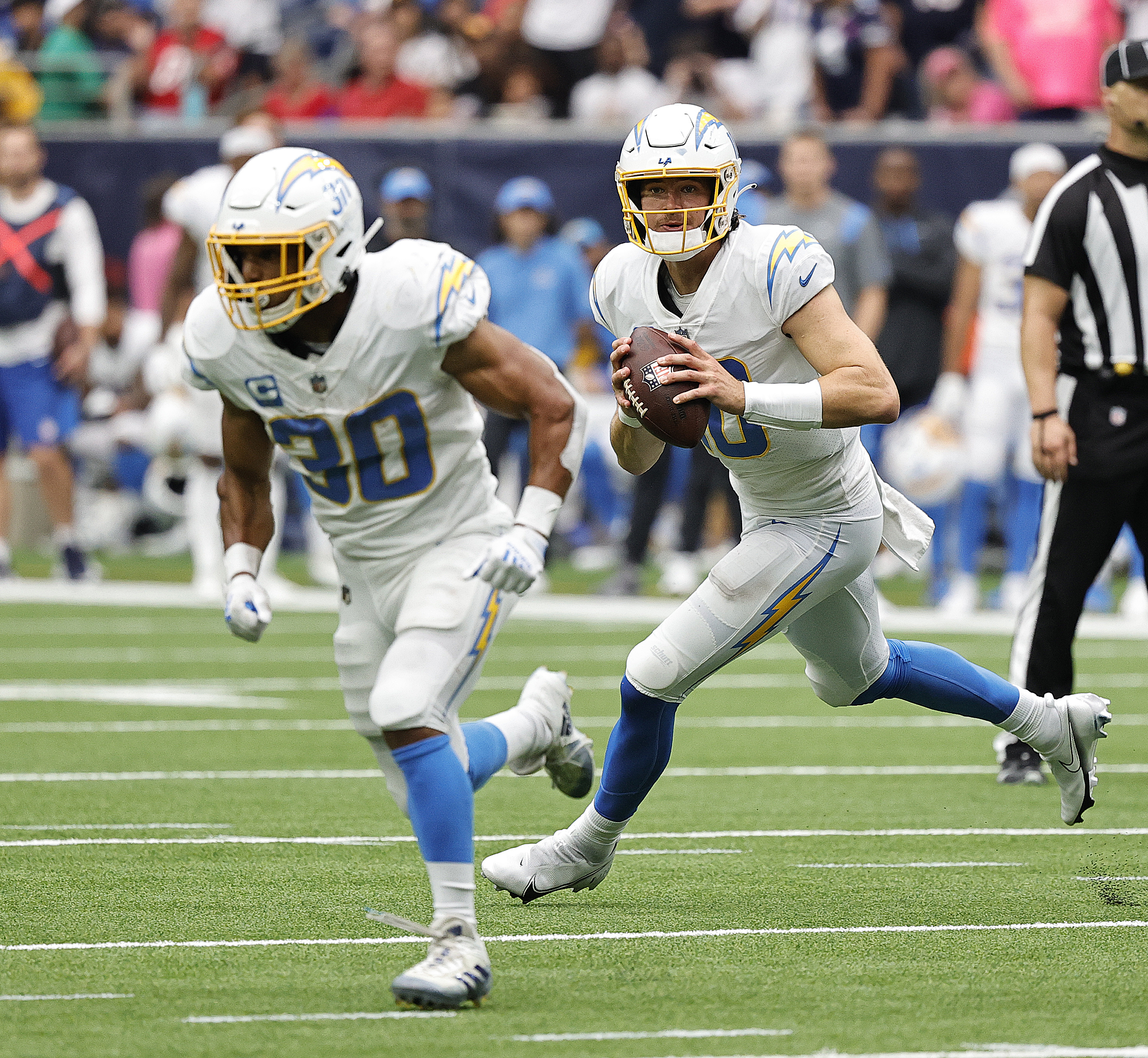 Justin Herbert #10 of the Los Angeles Chargers rolls out looking for a receiver against the Houston Texans at NRG Stadium on October 02, 2022 in Houston, Texas.