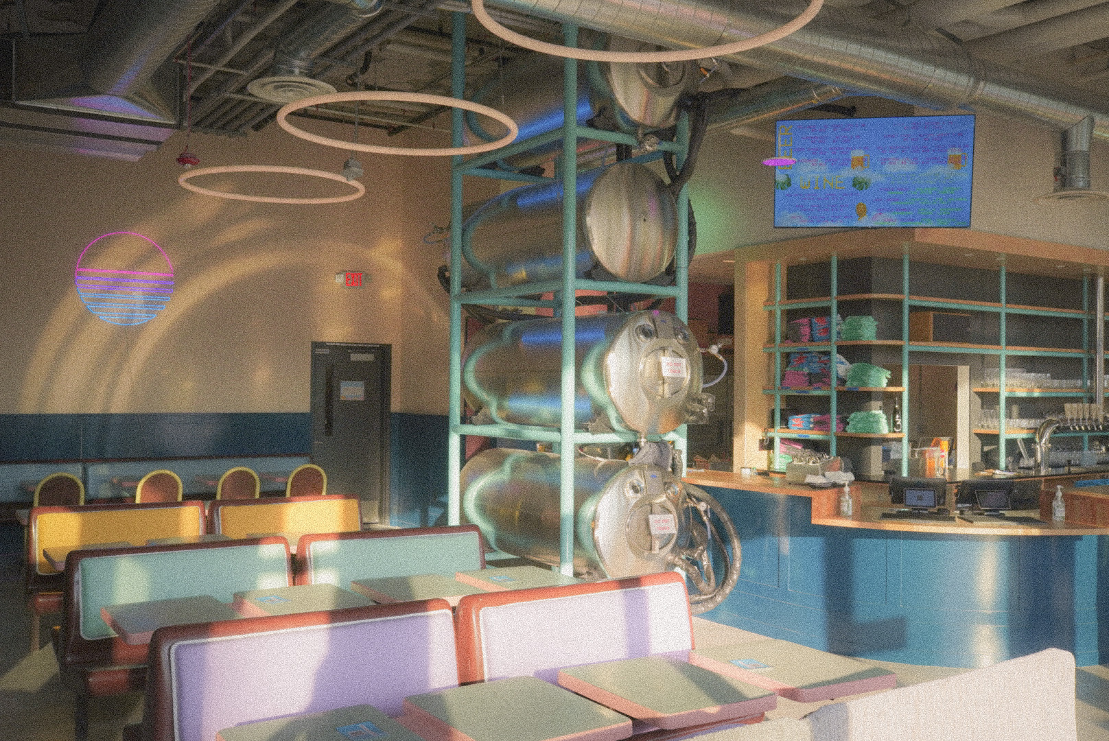 The interior of a brewery with pastel-colored booths and neon ring lights.