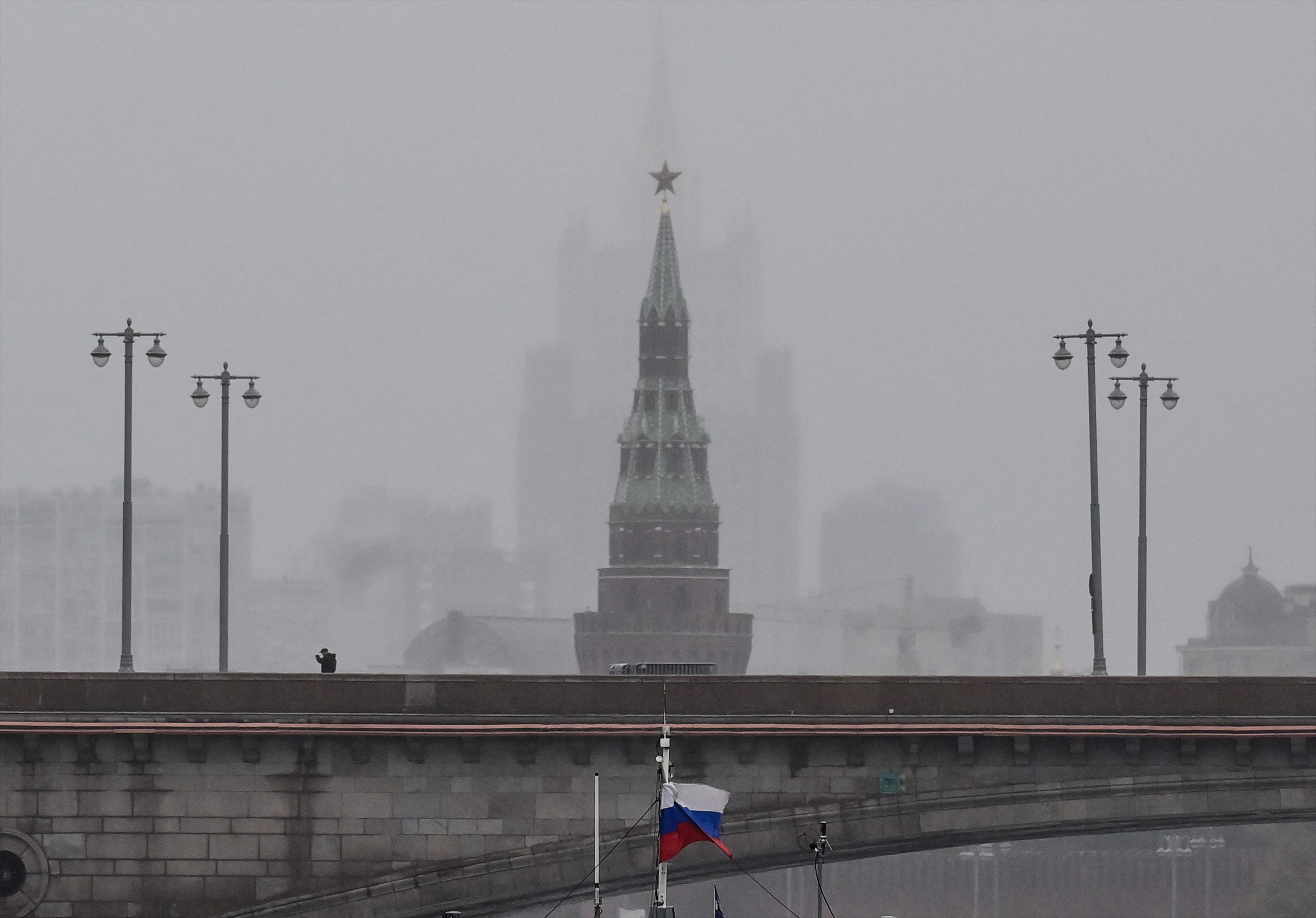 A pedestrian walks along a bridge over the Moskva River in front of the Vodovzvodnaya tower of the Kremlin and the Russian Foreign Ministry headquarters in central Moscow on October 4, 2022.