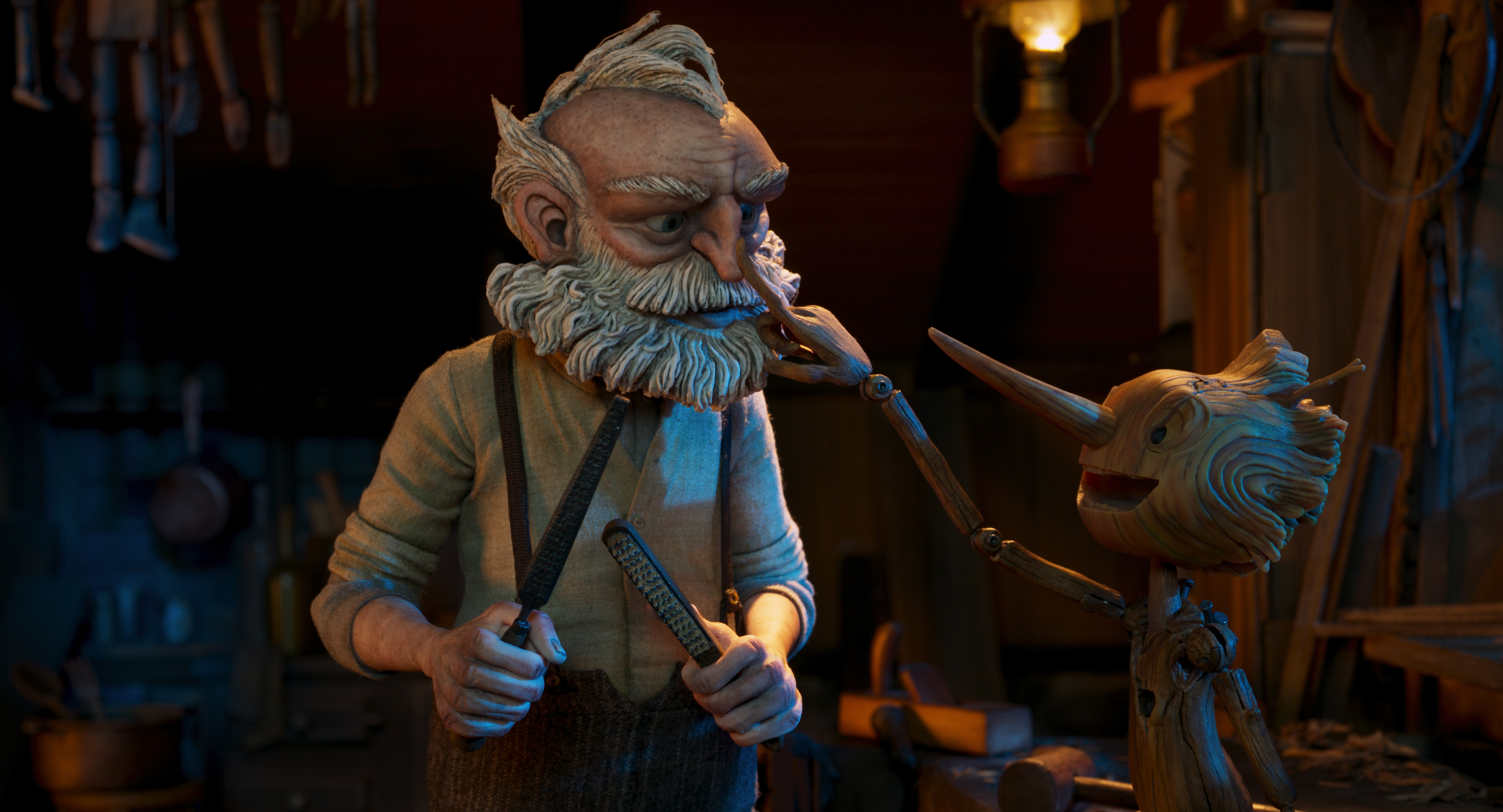 The wooden boy Pinocchio presses down Geppetto’s nose playfully. Geppetto is holding some tools