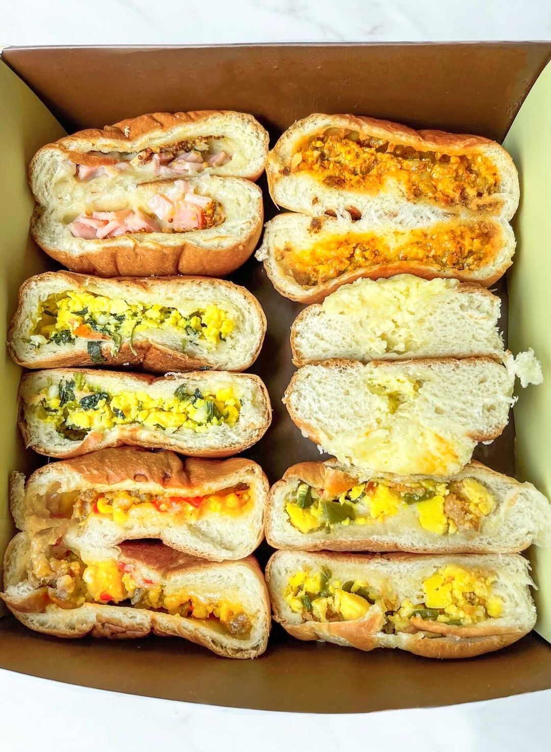 A box filled with halved kolaches with different colorful fillings.