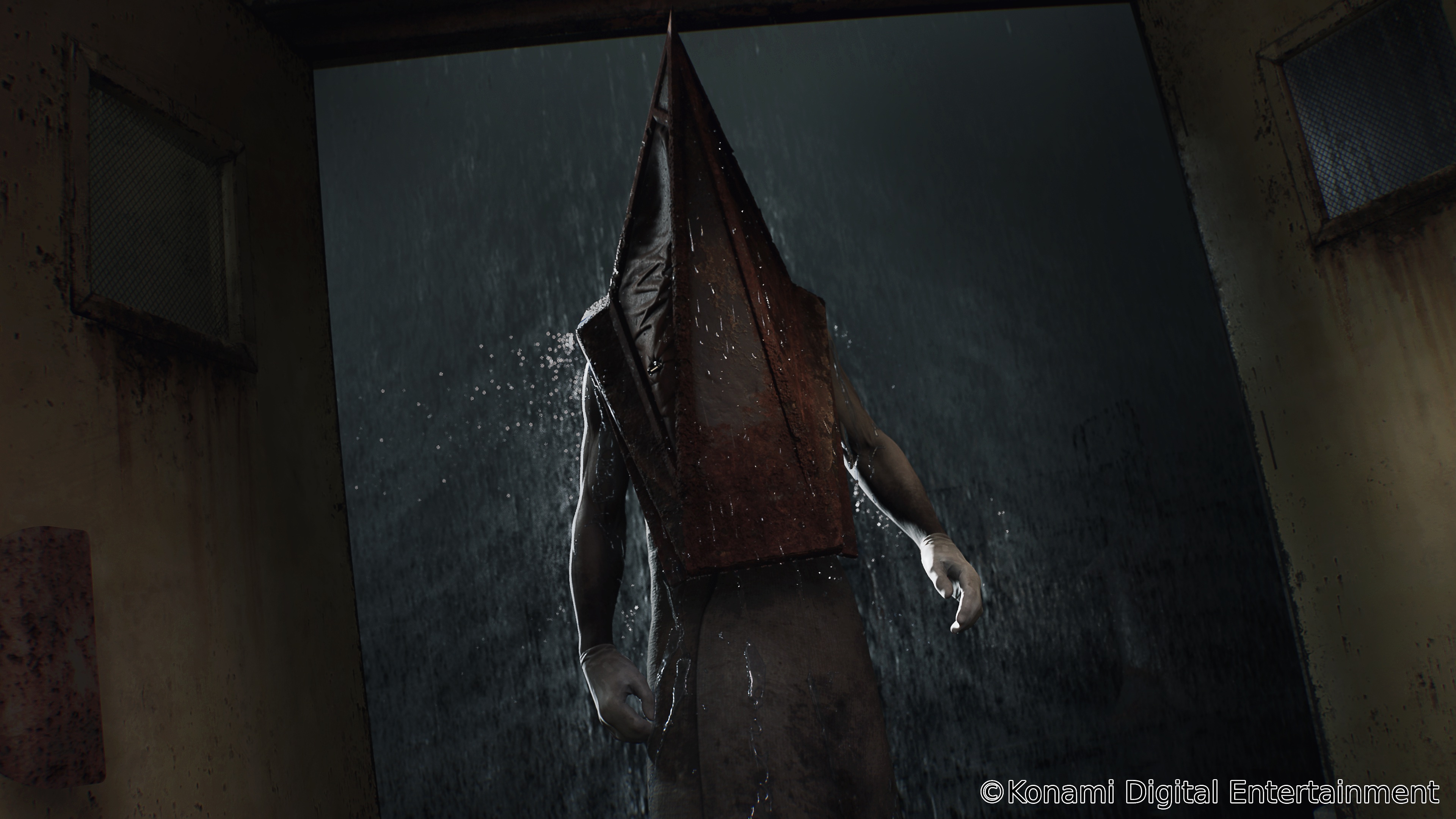Pyramid Head walks through the rain and through a pair of metal doors in a still from the Silent Hill 2 remake