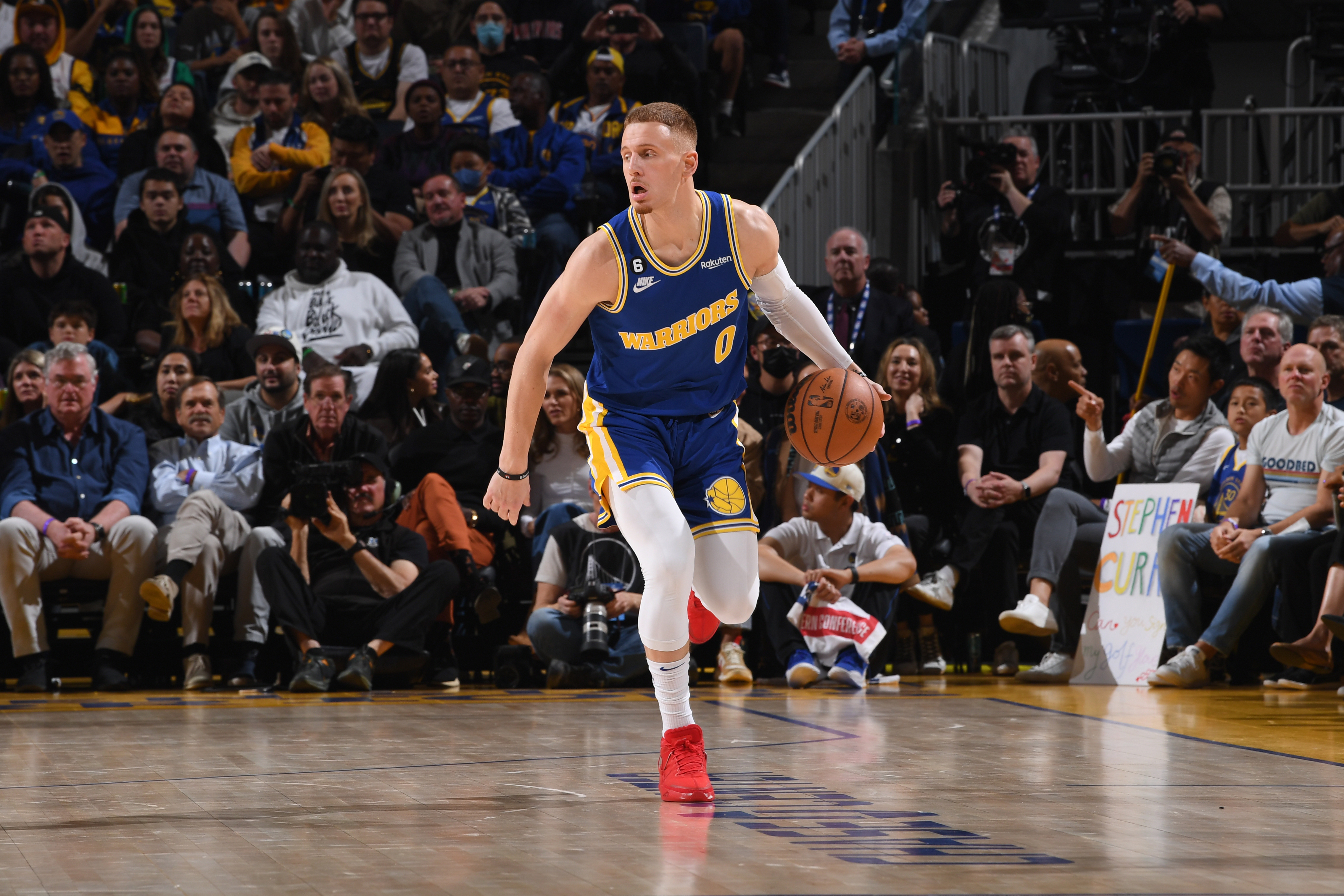 Donte DiVincenzo dribbling with his left hand in a throwback Warriors jersey