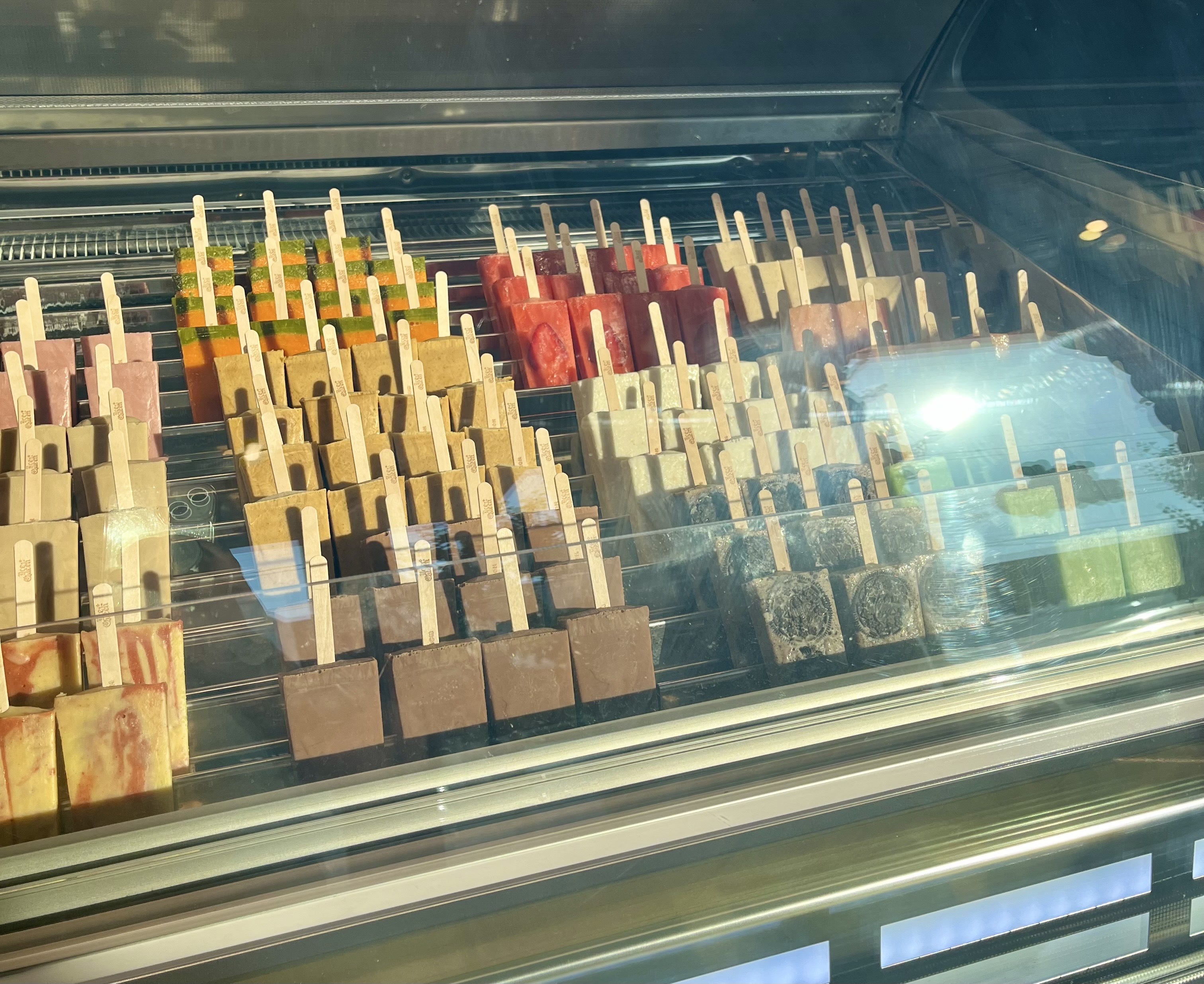 Rows of colorful popsicles sit displayed in a freezer case.