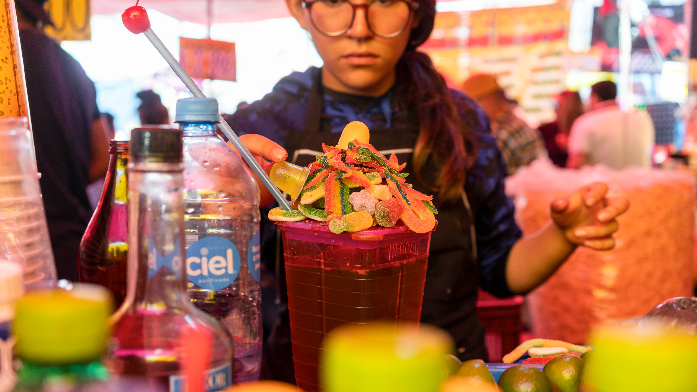 A woman stands behind a pitcher piled with gummy candies