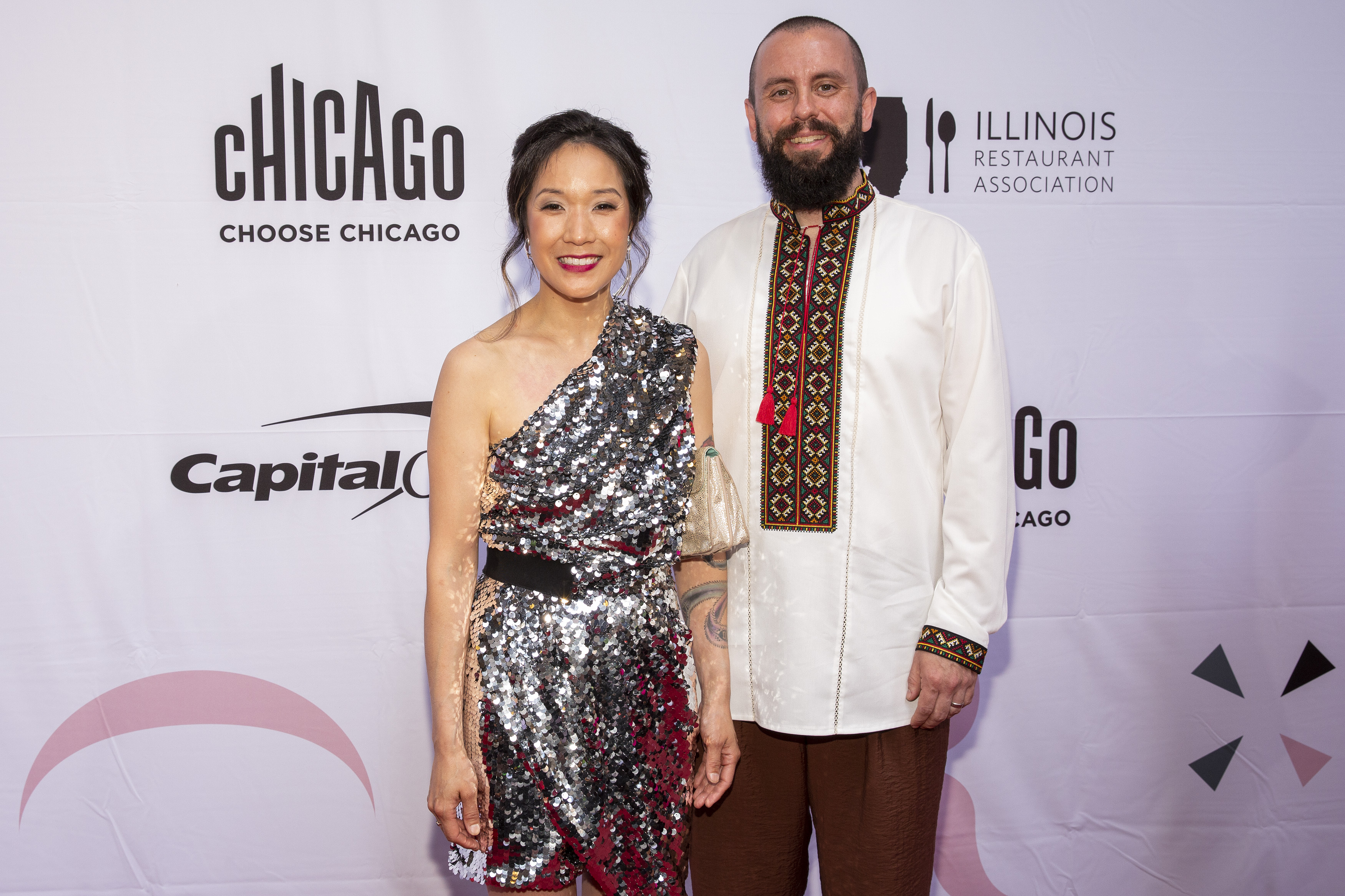 An Asian American woman and white man pose and smile on the red carpet at the James Beard awards.