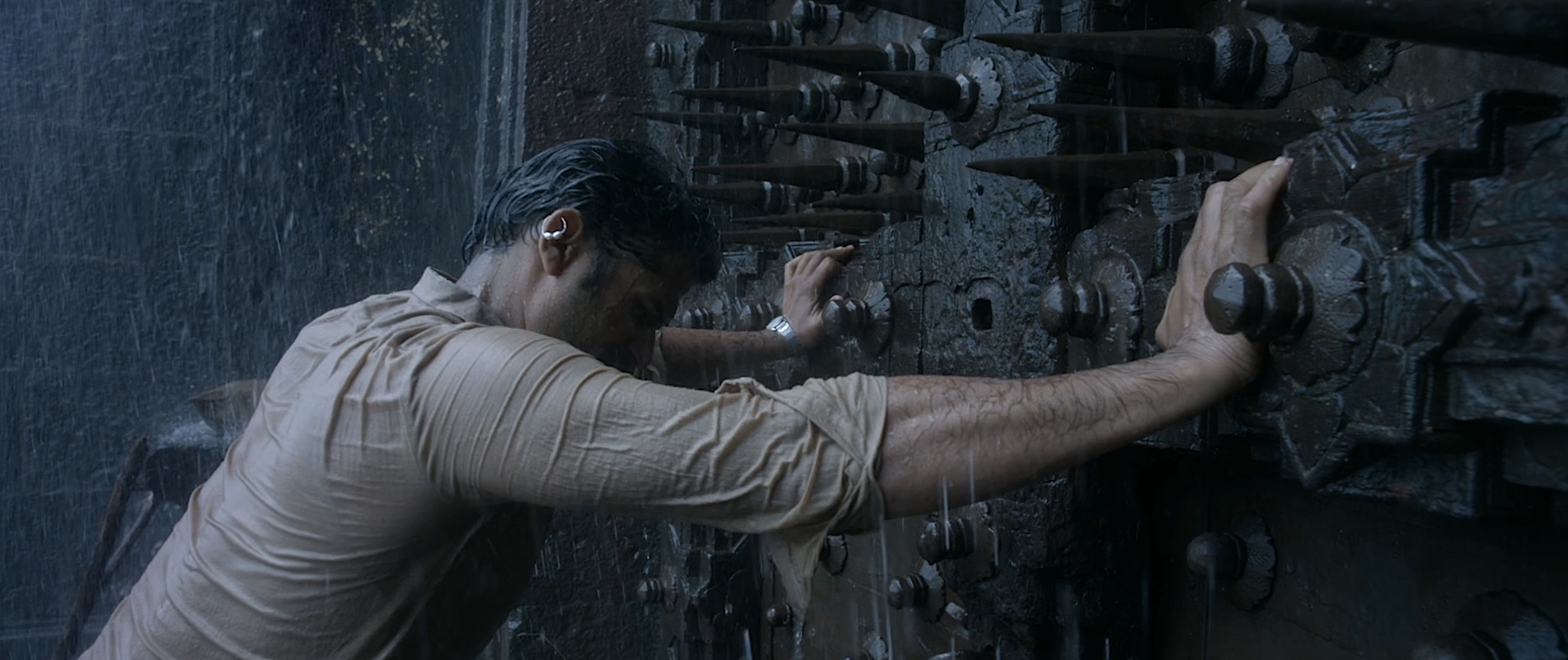 Vinayak (Sohum Shah) stands in drenching rain and throws his body weight against a giant metal door covered with vicious spikes in Tumbbad