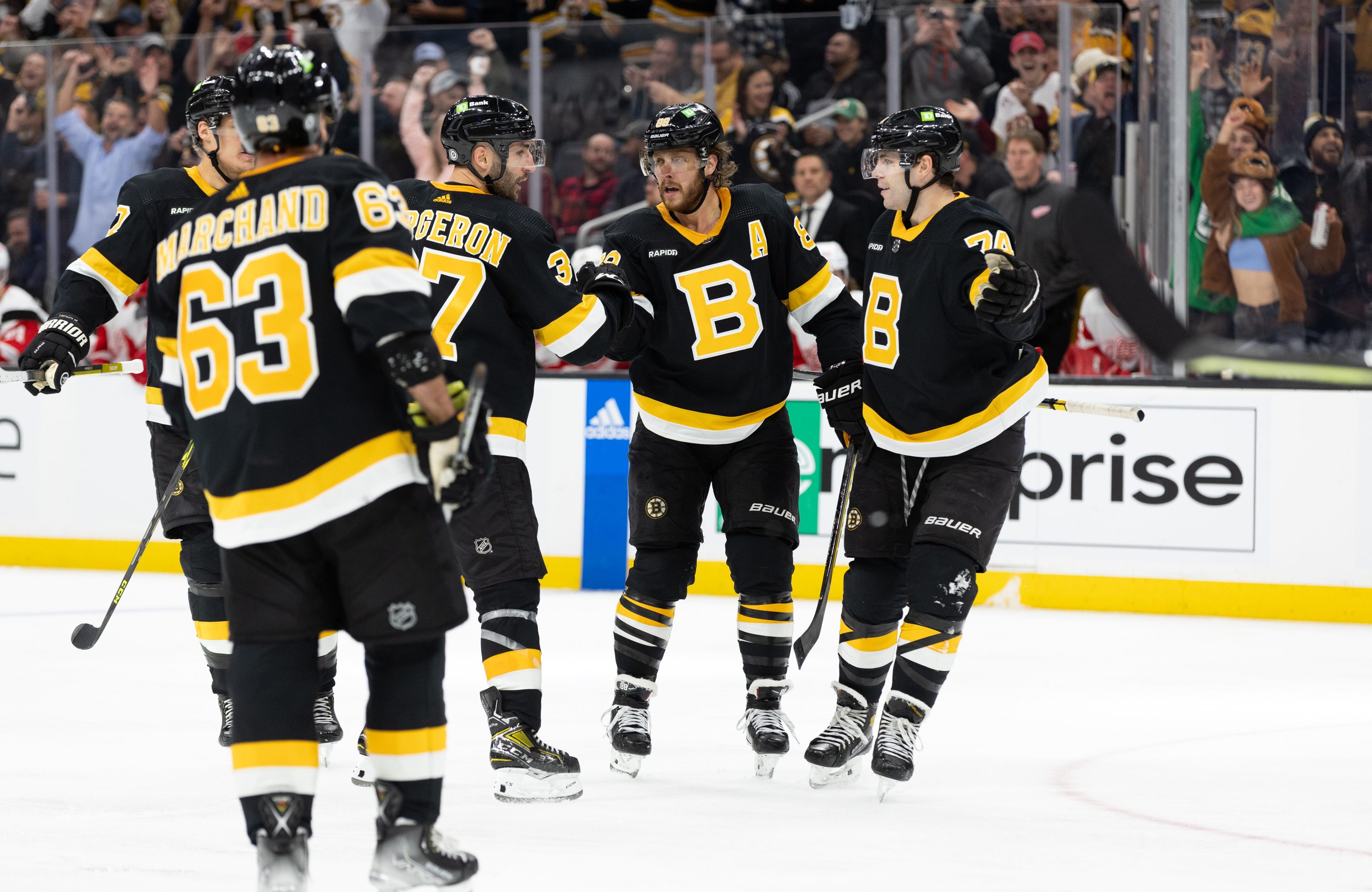 David Pastrnak of the Boston Bruins celebrates his goal against the Detroit Red Wings with his teammates Jake DeBrusk, Patrice Bergeron and Brad Marchand during the third period at the TD Garden on October 27, 2022 in Boston, Massachusetts. The Bruins won 5-1.