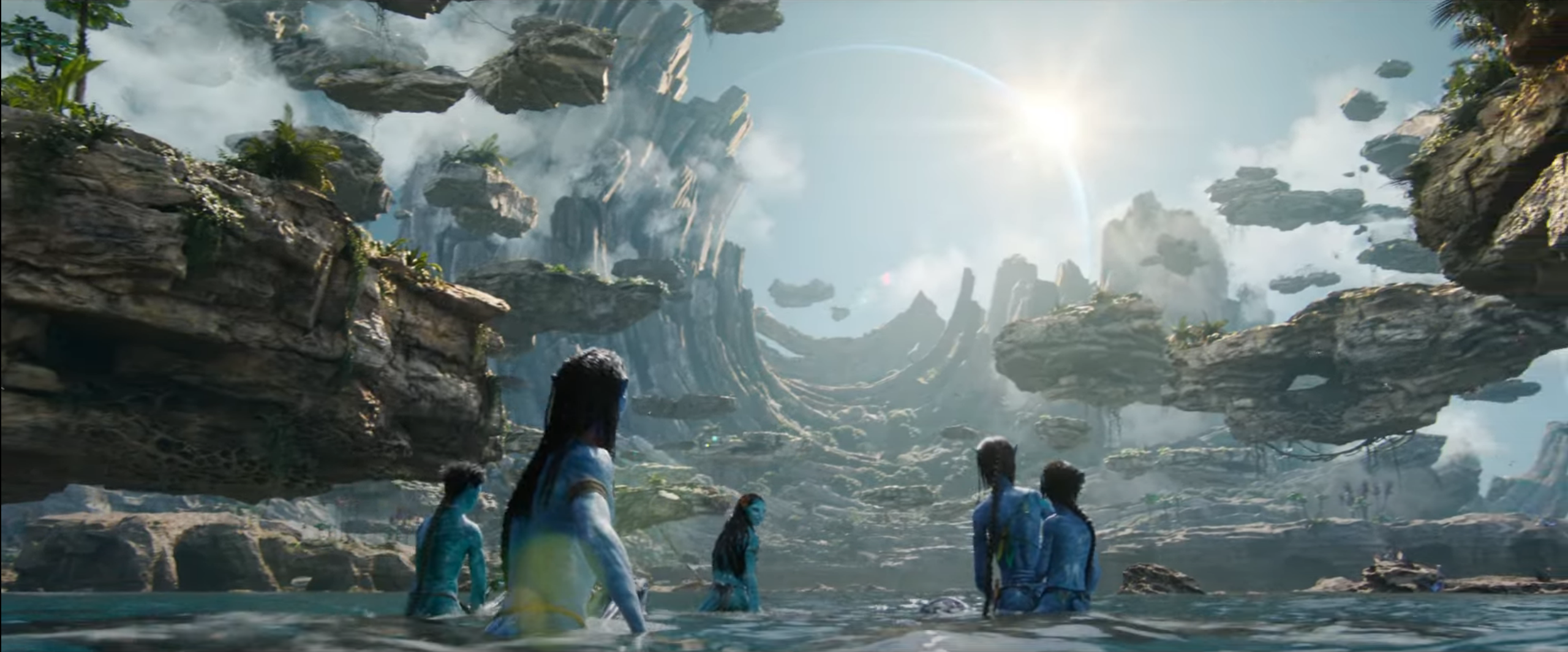 Blue Na’vi aliens walk through water against a fantastical backdrop of floating rocks