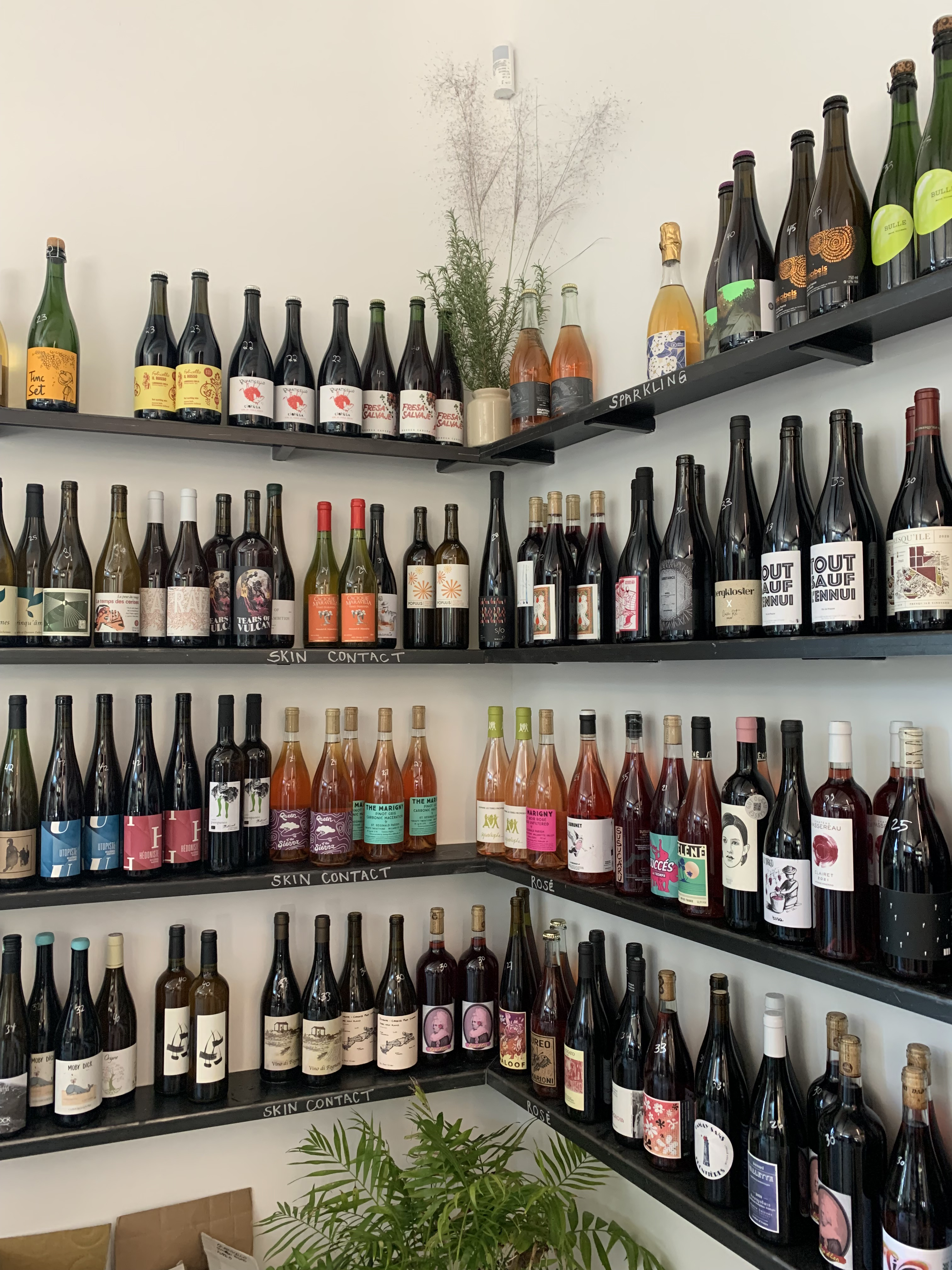 A corner shop with wine bottles on open shelving.