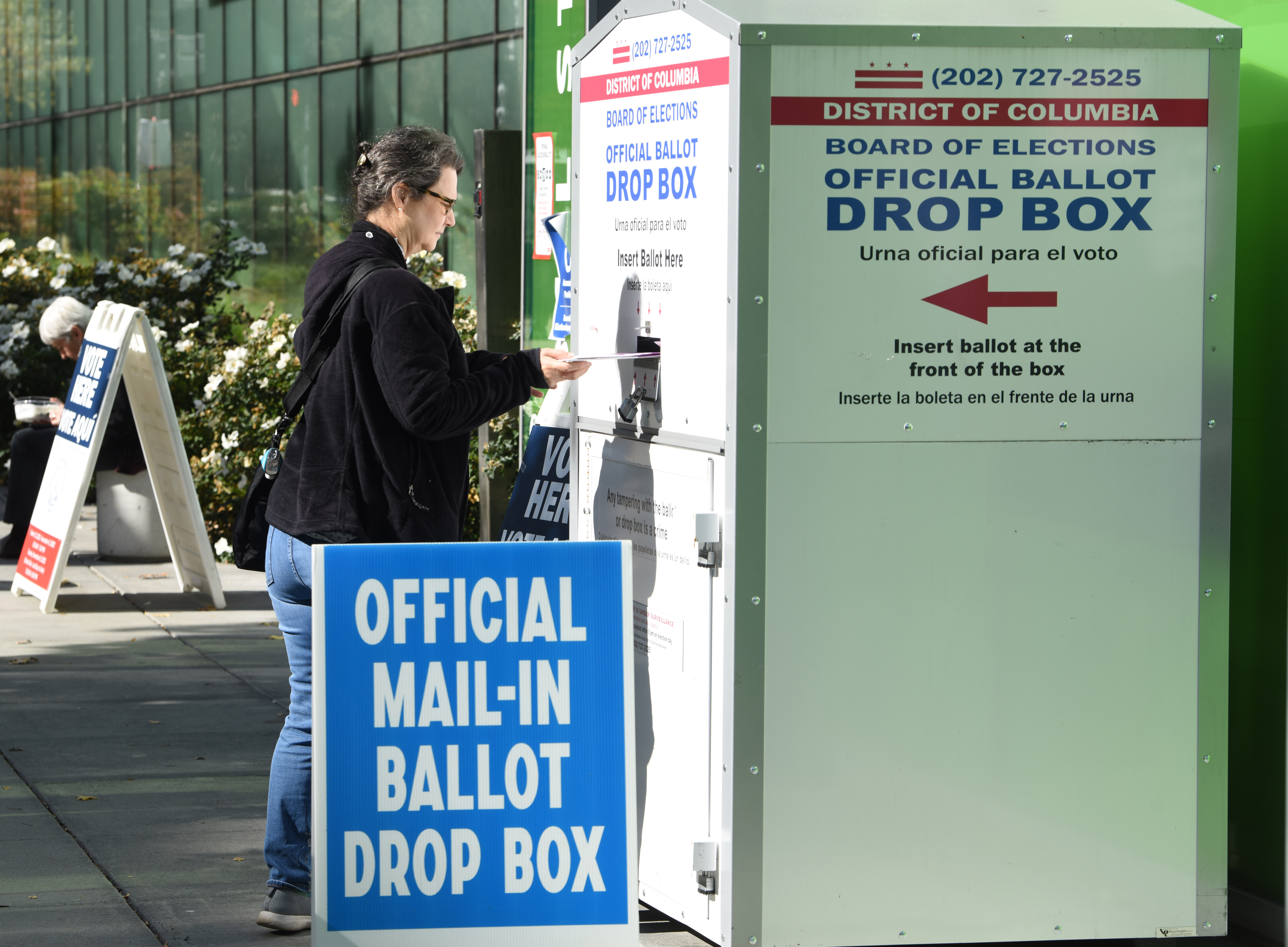 Woman drops ballot in a dropbox.