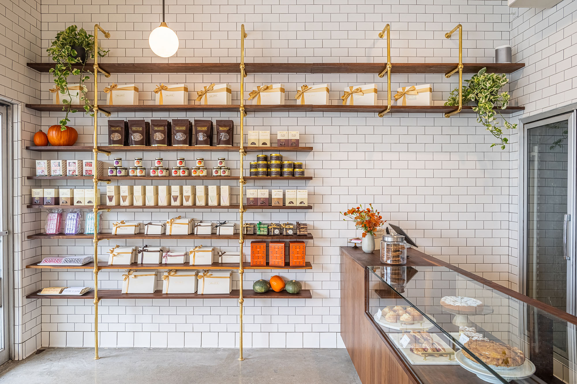 Wood shelves containing chocolates and treats on a tiled white wall at Valerie Confections in Glendale.