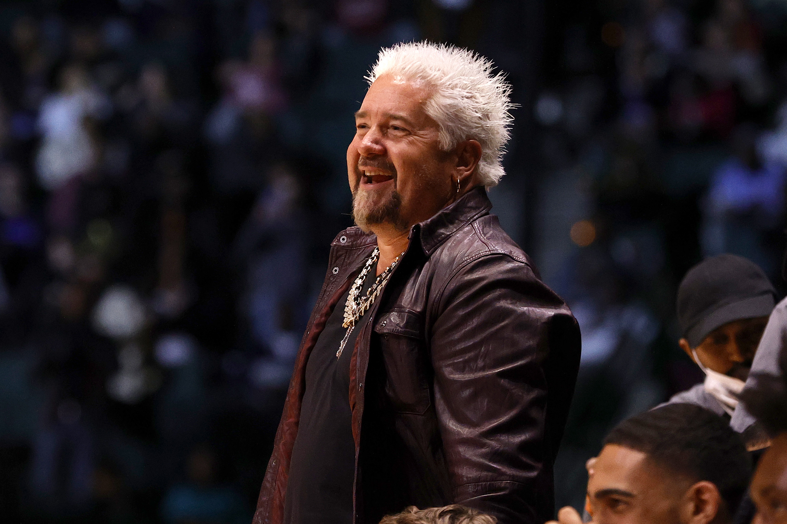 Man with blonde spiky hair and leather jacket smiles.
