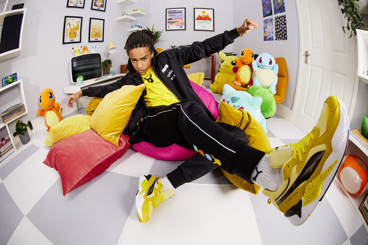 A photo of a person wearing the Puma Pikachu sneakers. The image using a fish-eye lens as the model leans back with their arms held open. 