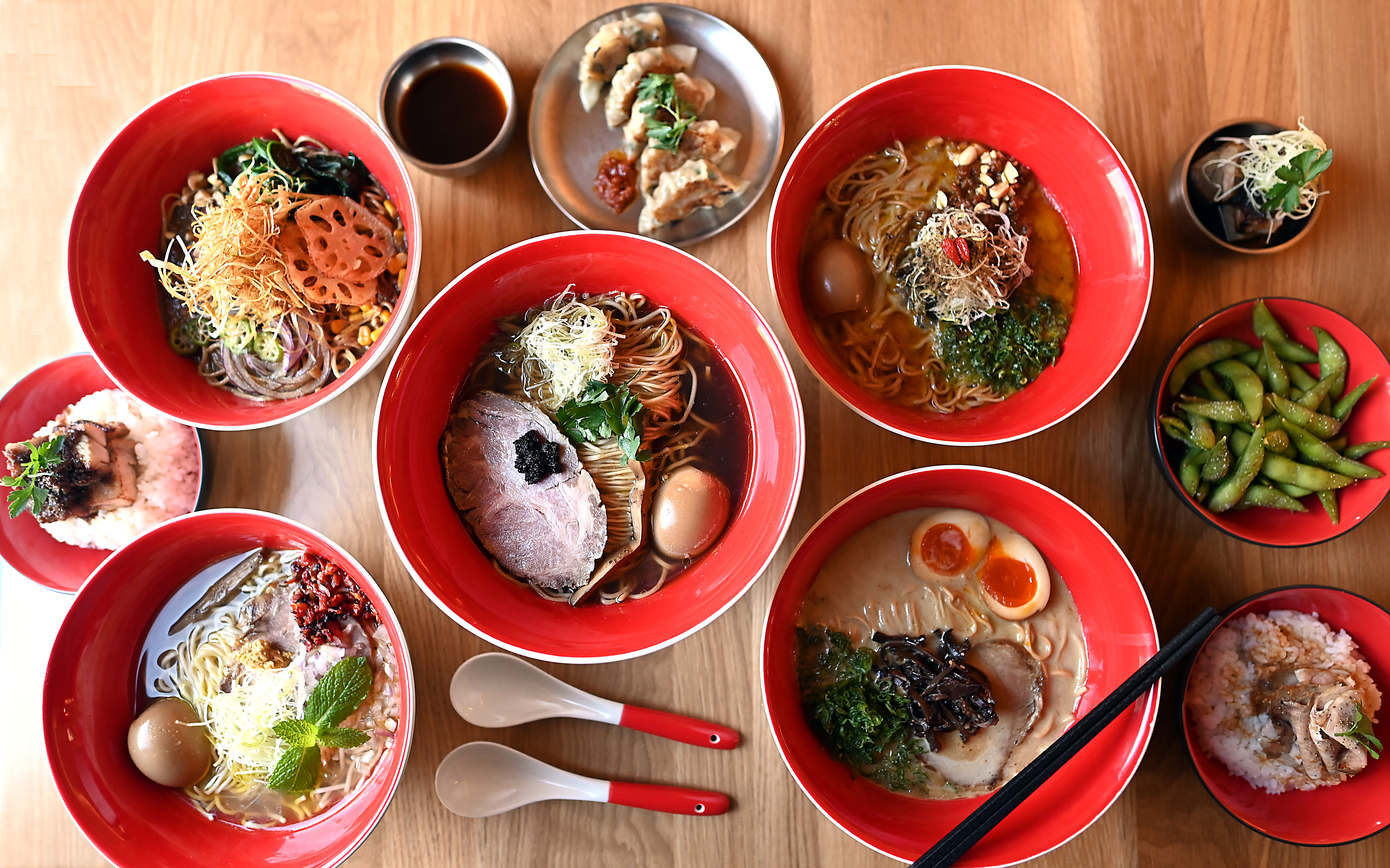 Five bowls of ramen and sides on a table.