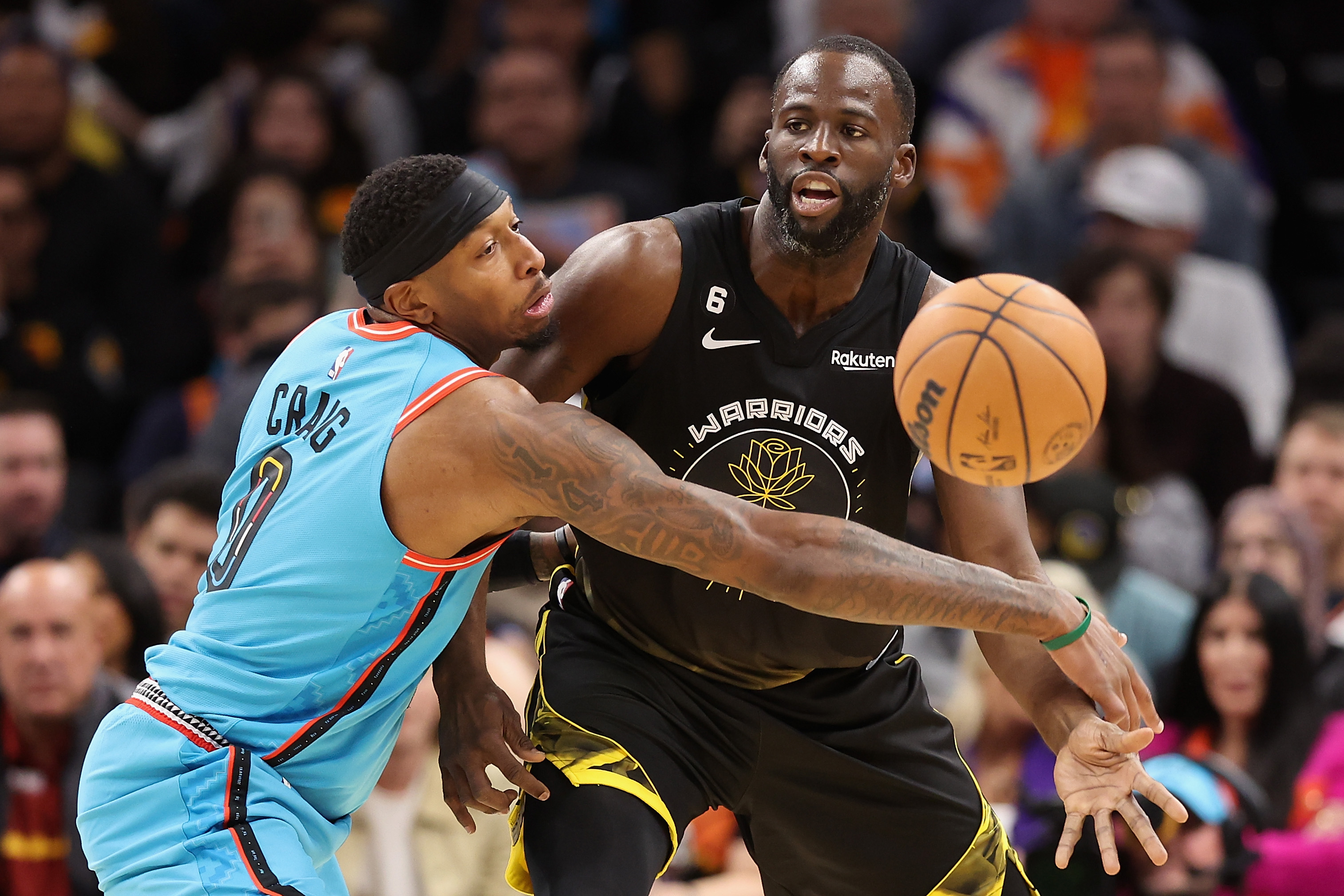Draymond Green passing the ball while defended by Torrey Craig