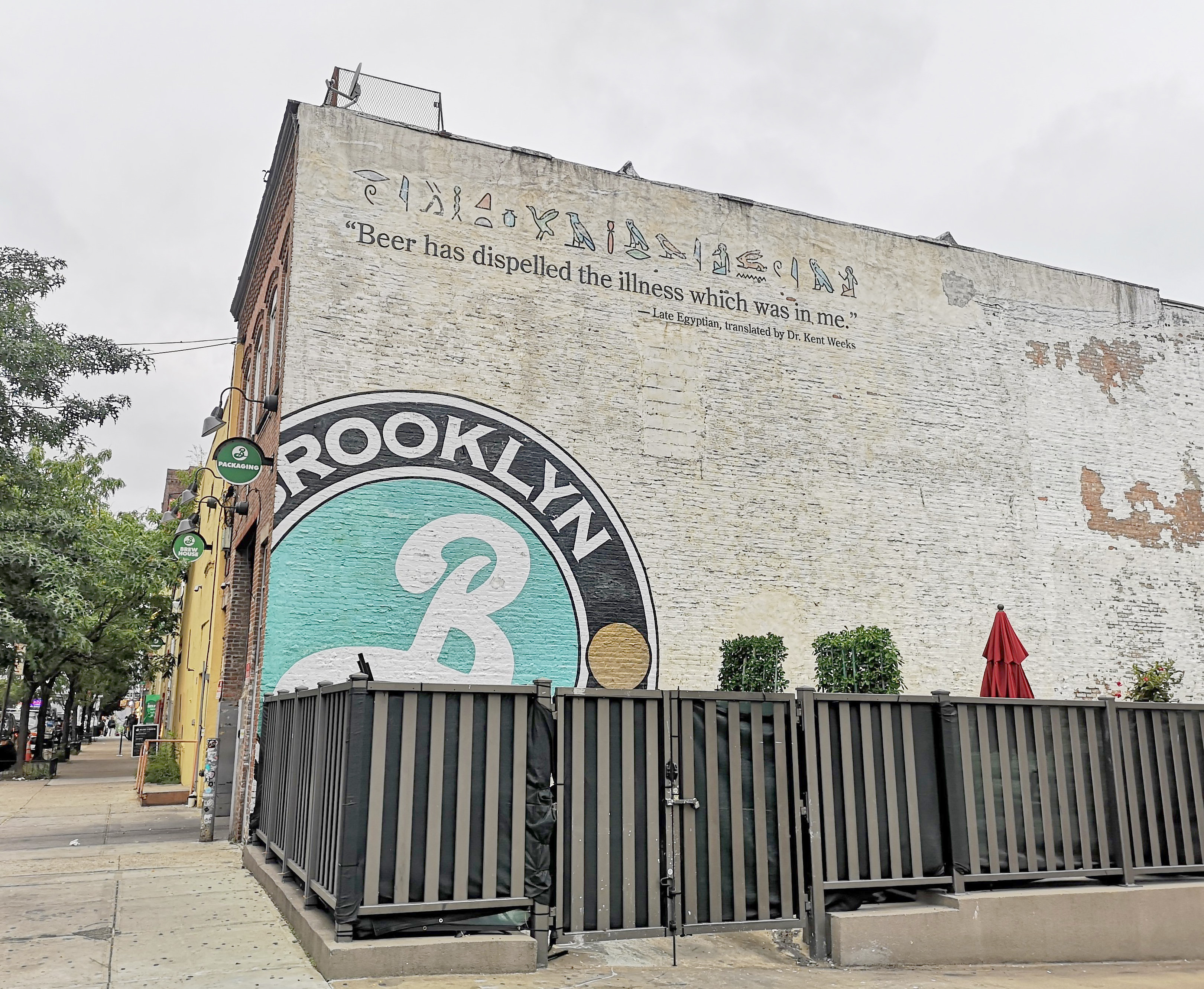 Outside of a Williamsburg building whose side is decorated with the logo of Brooklyn Brewery.