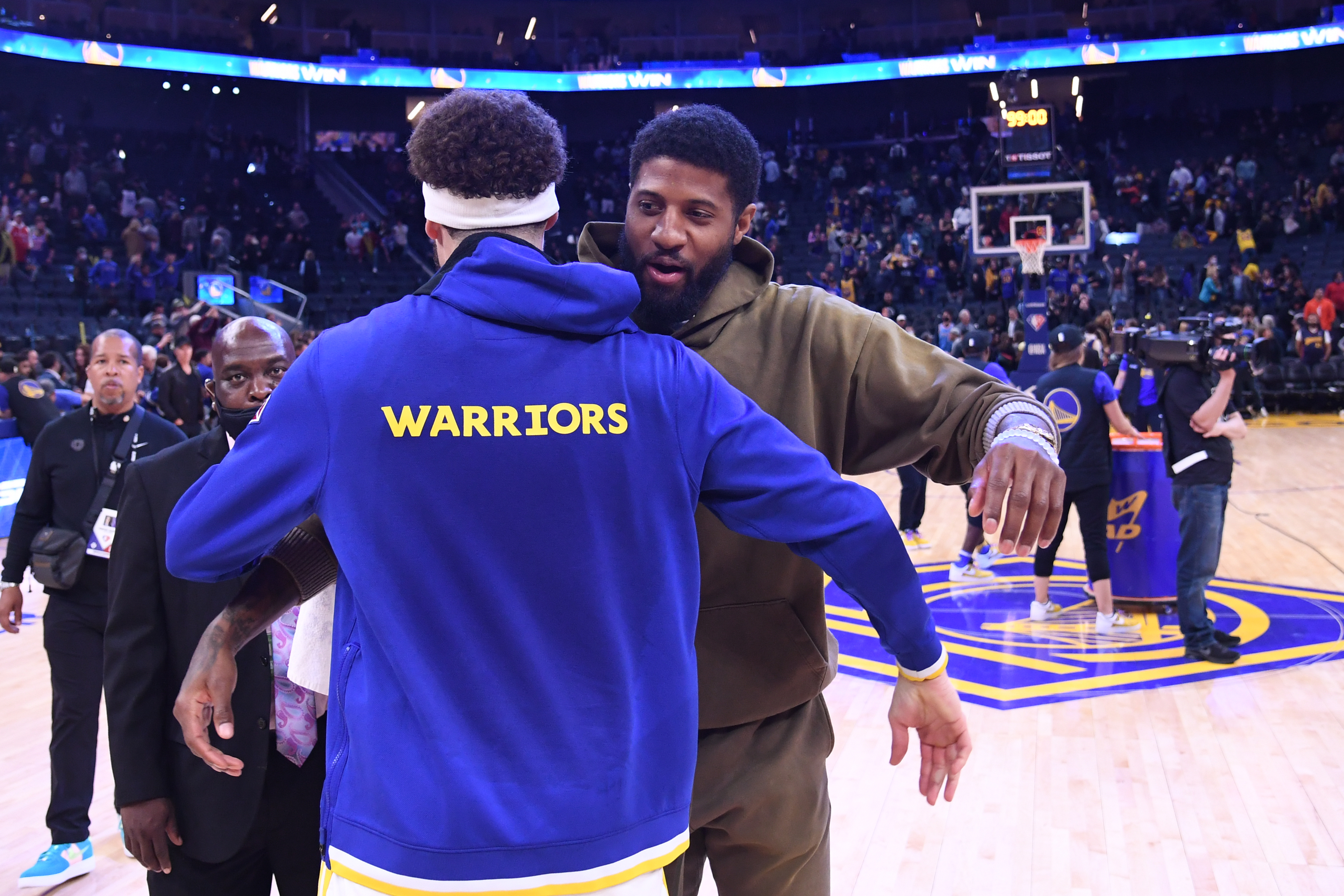 Paul George, in street clothes, hugging Klay Thompson