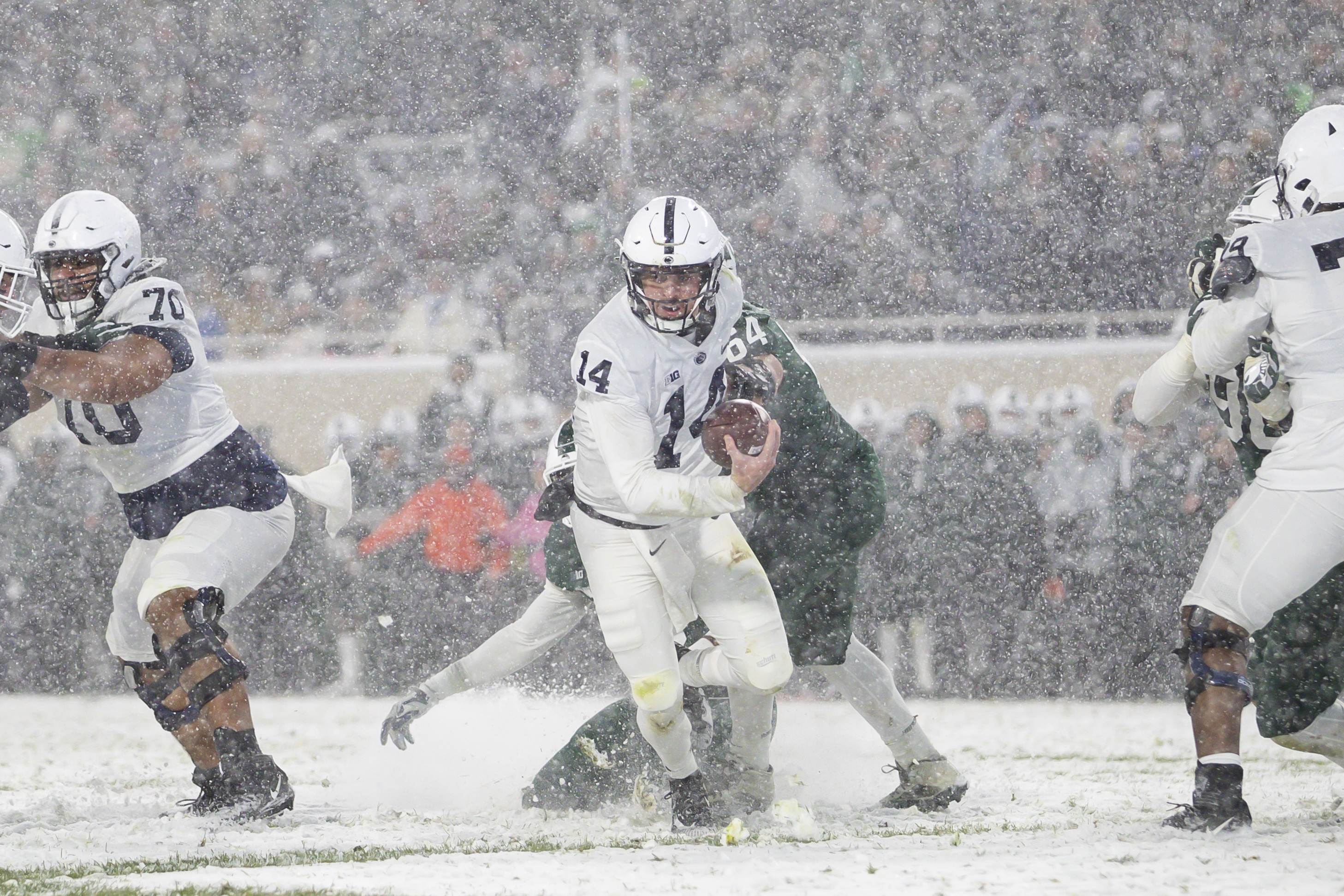 Nov 27, 2021; East Lansing, Michigan, USA; Penn State Nittany Lions quarterback Sean Clifford (14) tries to run away from Michigan State Spartans defensive tackle Jacob Slade (64) during the fourth quarter at Spartan Stadium.