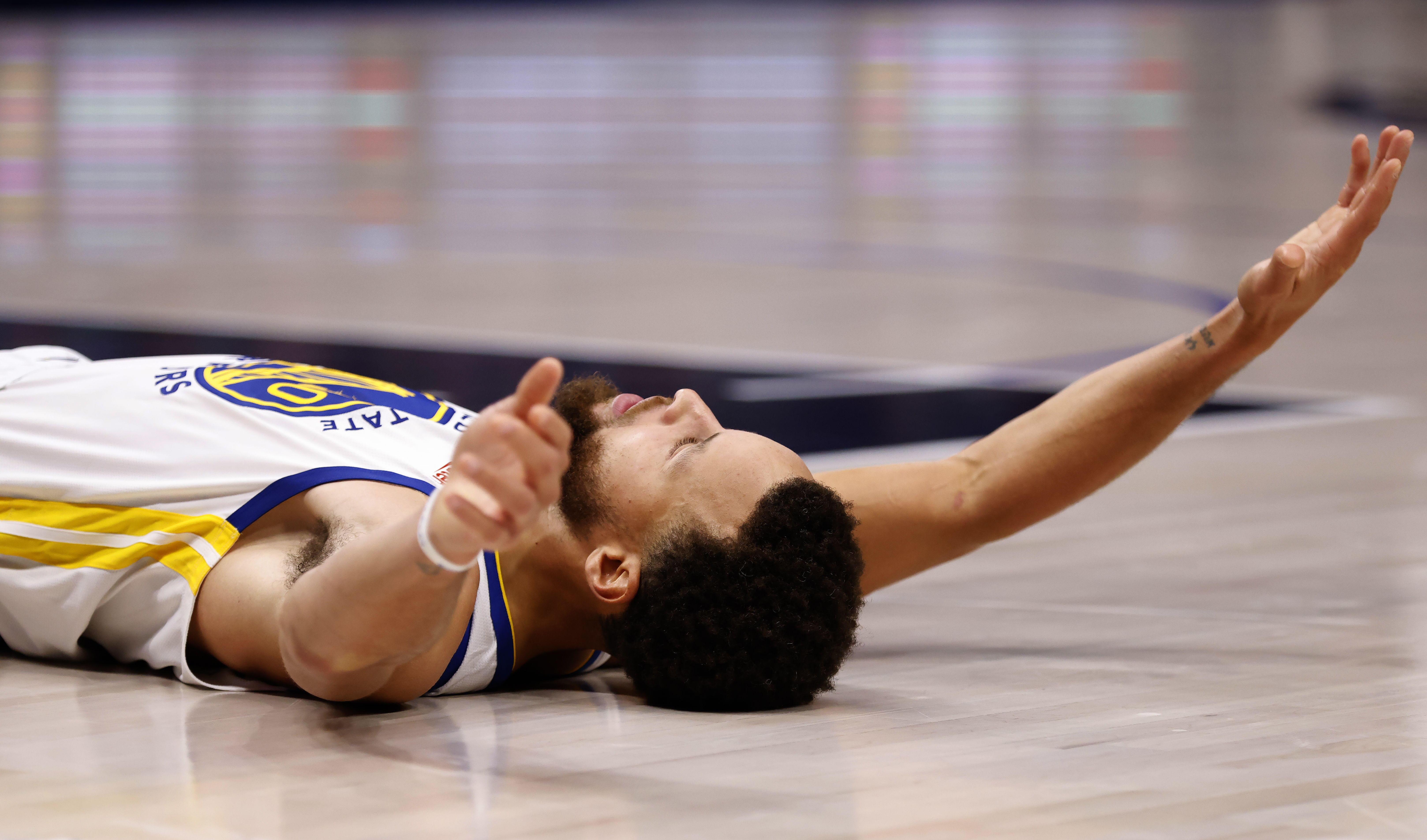 Steph Curry laying on his back with his arms extended