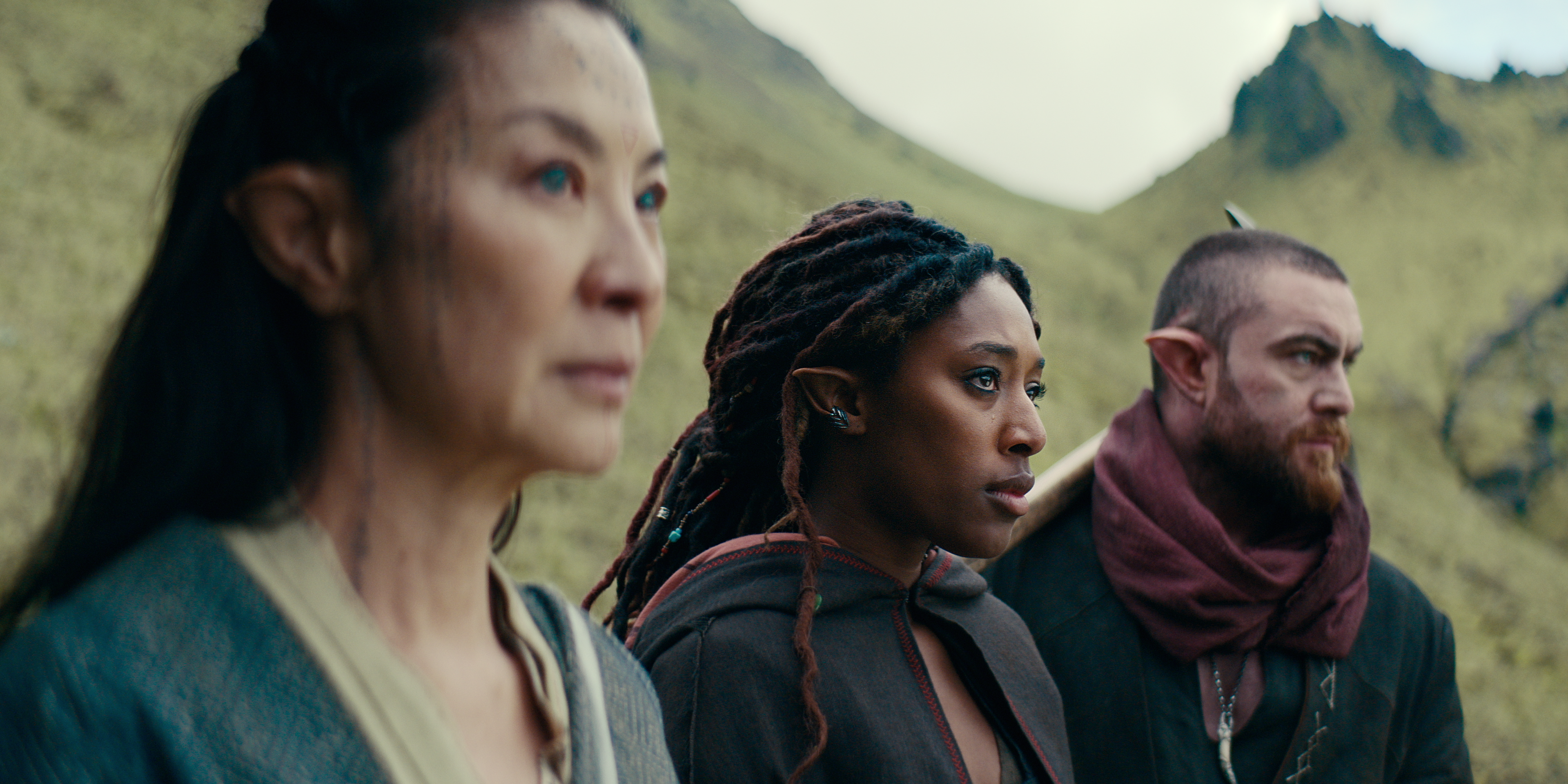 three elves — one played by michelle yeoh — stand and look to the right. next to michelle yeoh is a young Black woman and next to her is a white bearded man. they all have point ears