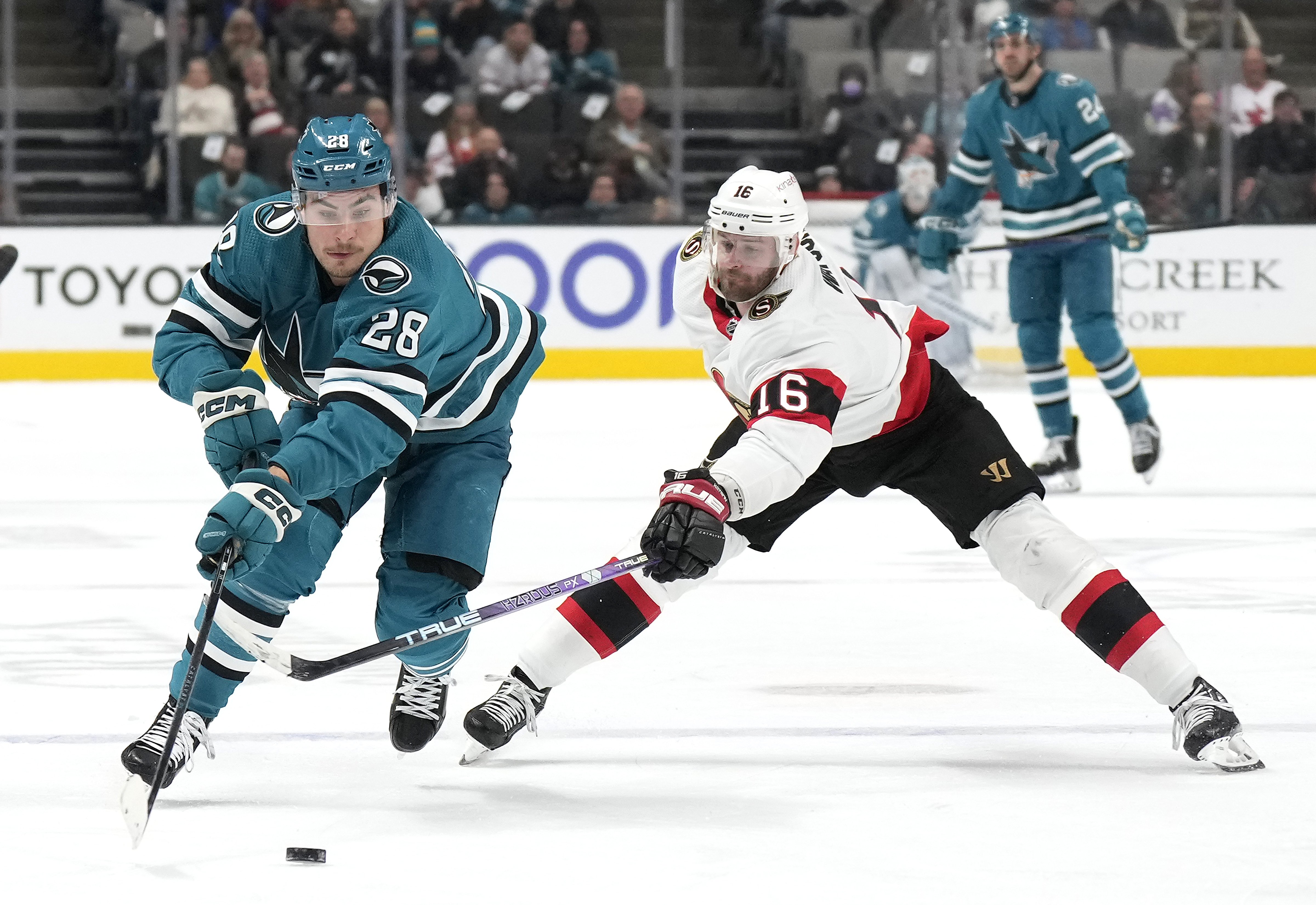 Timo Meier #28 of the San Jose Sharks skates up ice with the puck pursued by Austin Watson #16 of the Ottawa Senators during the second period of an NHL hockey game at SAP Center on November 21, 2022 in San Jose, California.