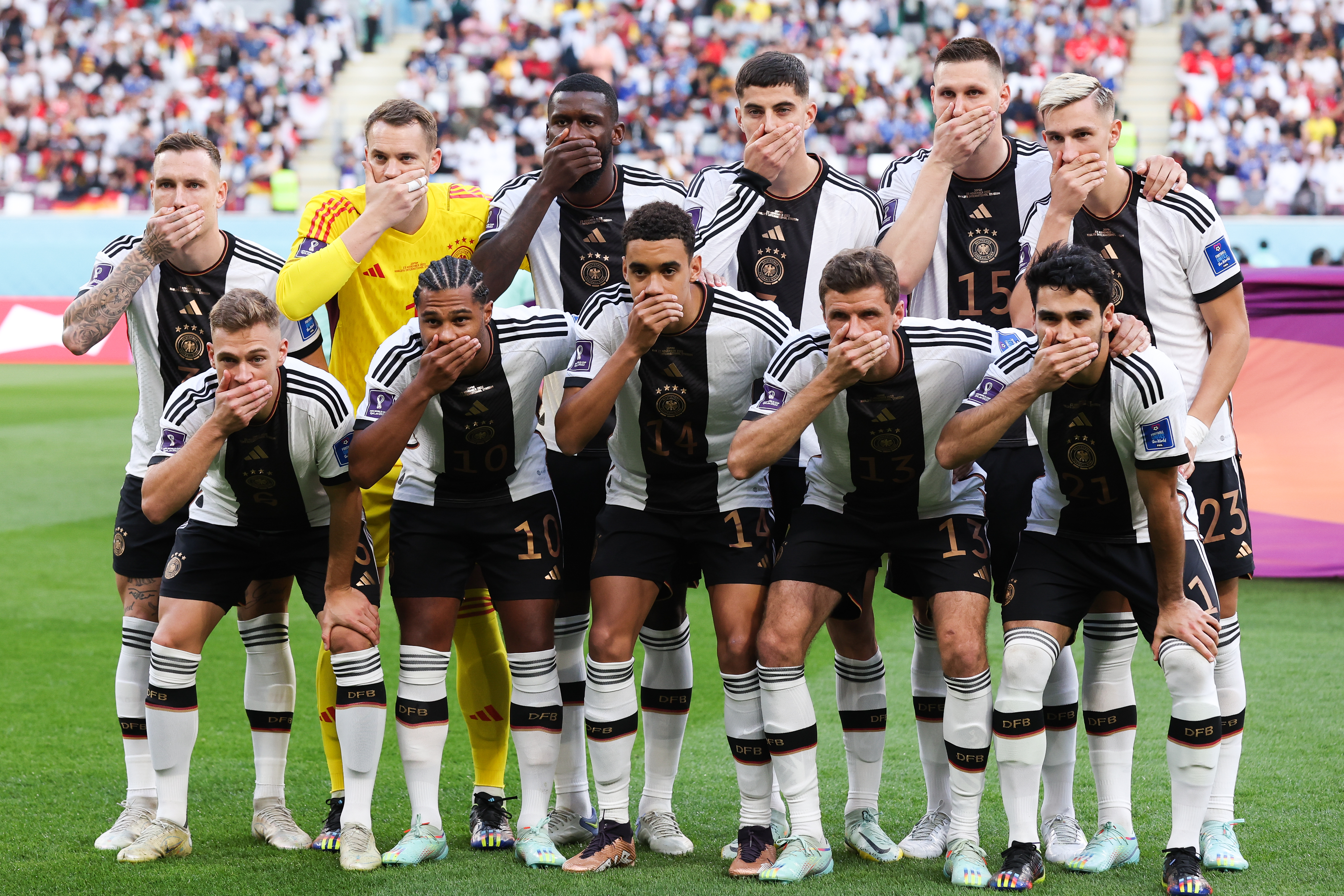 German soccer players cover their mouths during a photo op for the 2022 FIFA World Cup in Qatar.