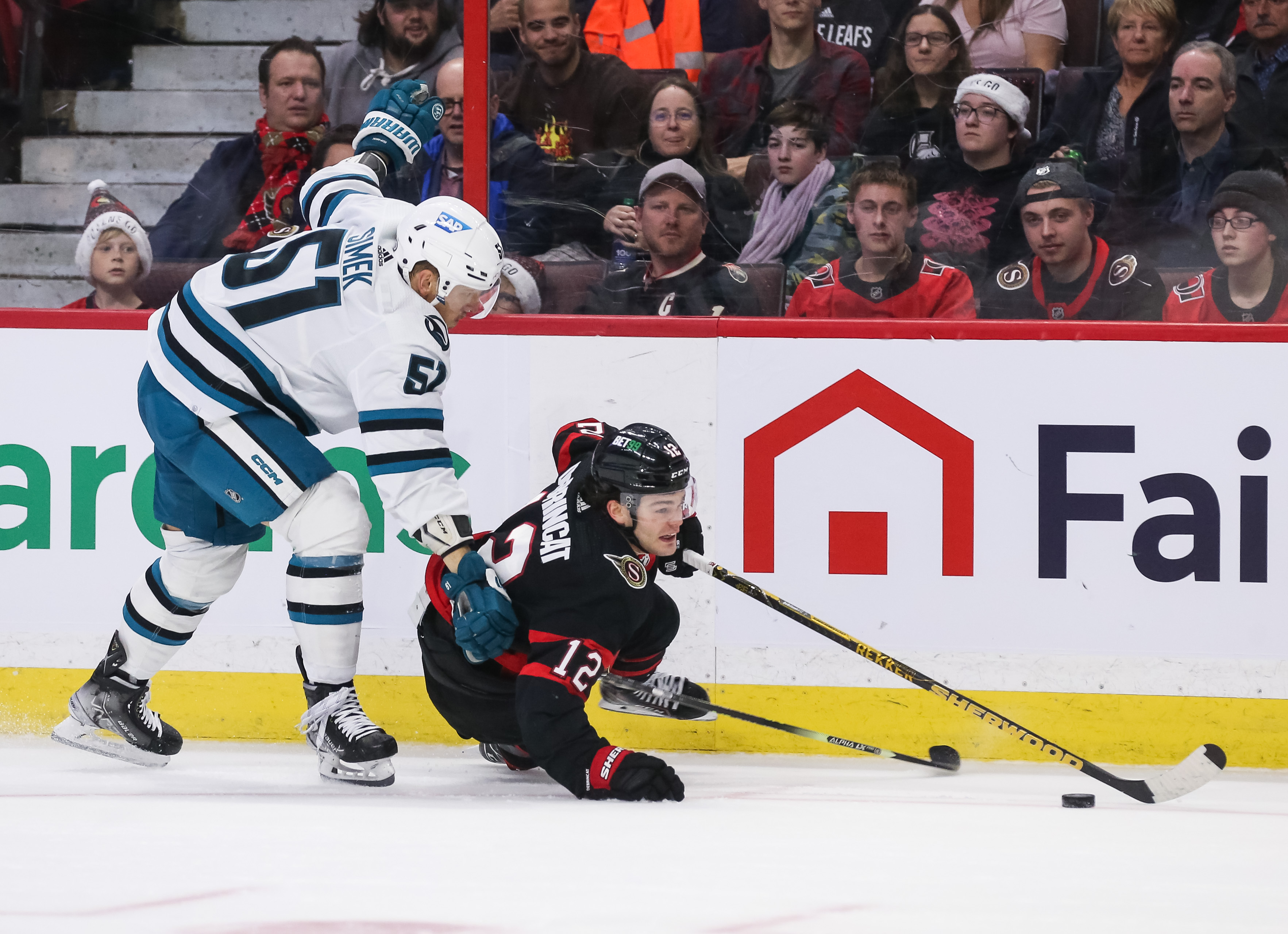 Radim Simek #51 of the San Jose Sharks holds Alex DeBrincat #12 of the Ottawa Senators during the second period at Canadian Tire Centre on December 03, 2022 in Ottawa, Ontario, Canada. Simek was called for a two-minute holding penalty on the play.