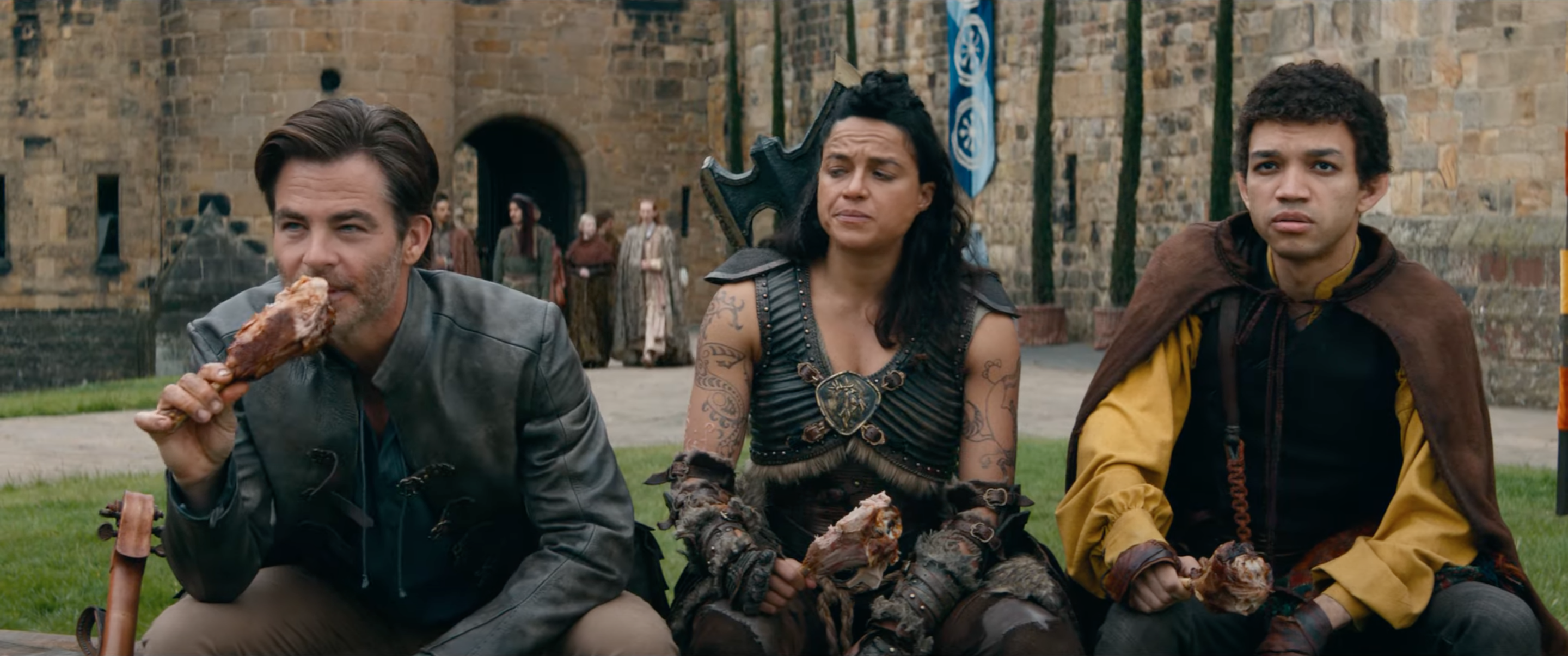 Chris Pine, Michelle Rodriguez, and Justice Smith sit and eat turkey legs in Dungeons &amp; Dragons: Honor Among Thieves