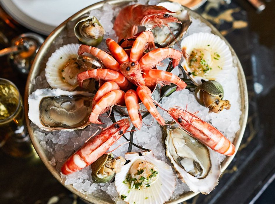A large seafood tower on multiple levels, with prawns; oysters; scallops; and whelks.