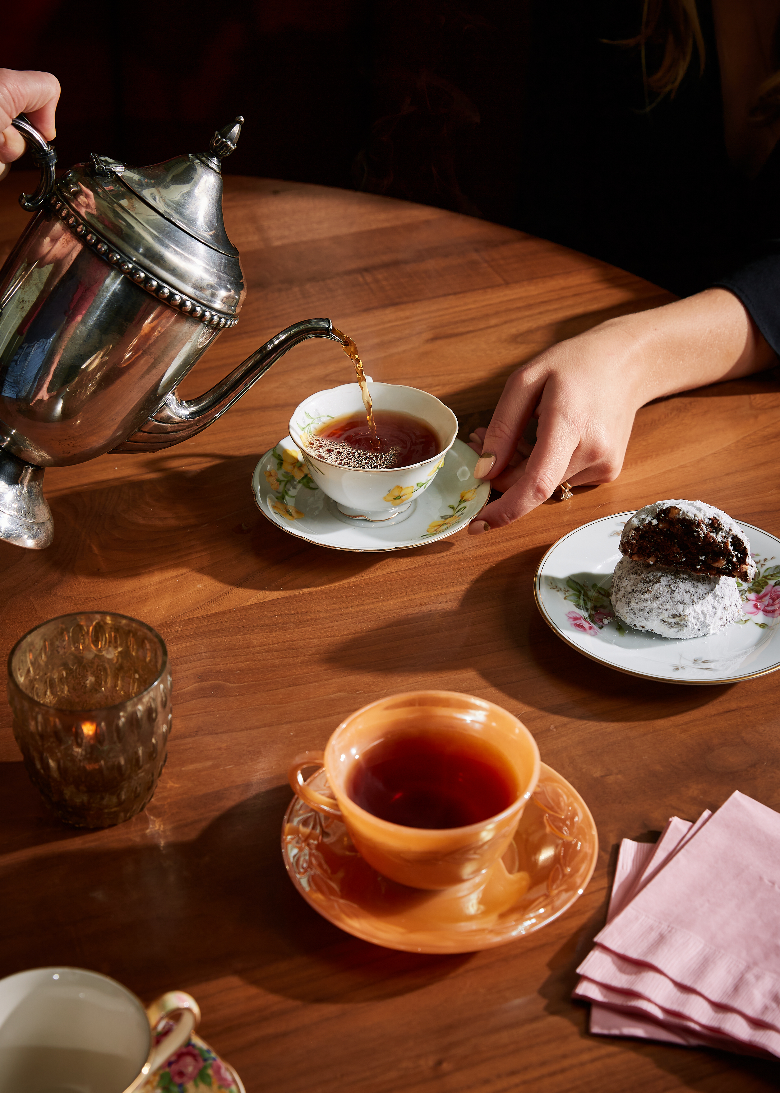 Tea is poured into a tea cup from a silver pot.