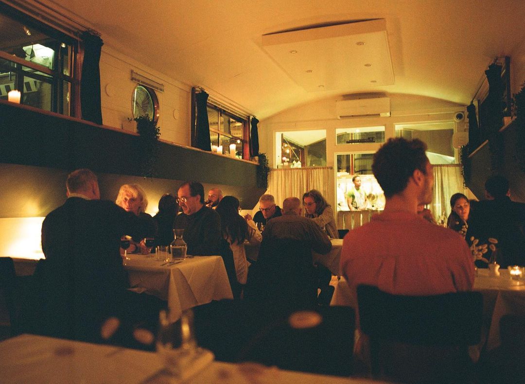 People sitting inside a restaurant under dim orange light.
