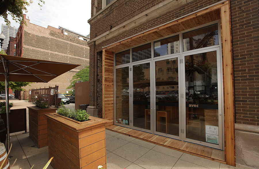 The exterior storefront of a restaurant with windows and a patio.