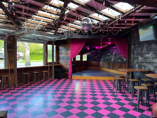 A checkered floor in black and pink in front of a stage with a pink curtain drawn back.