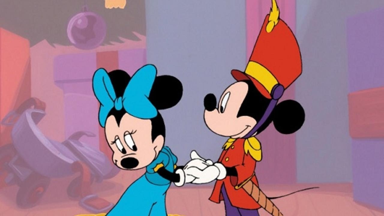minnie as maria in the nutcracker and mickey as the nutcracker; they hold hands and minnie is looking away, blushing