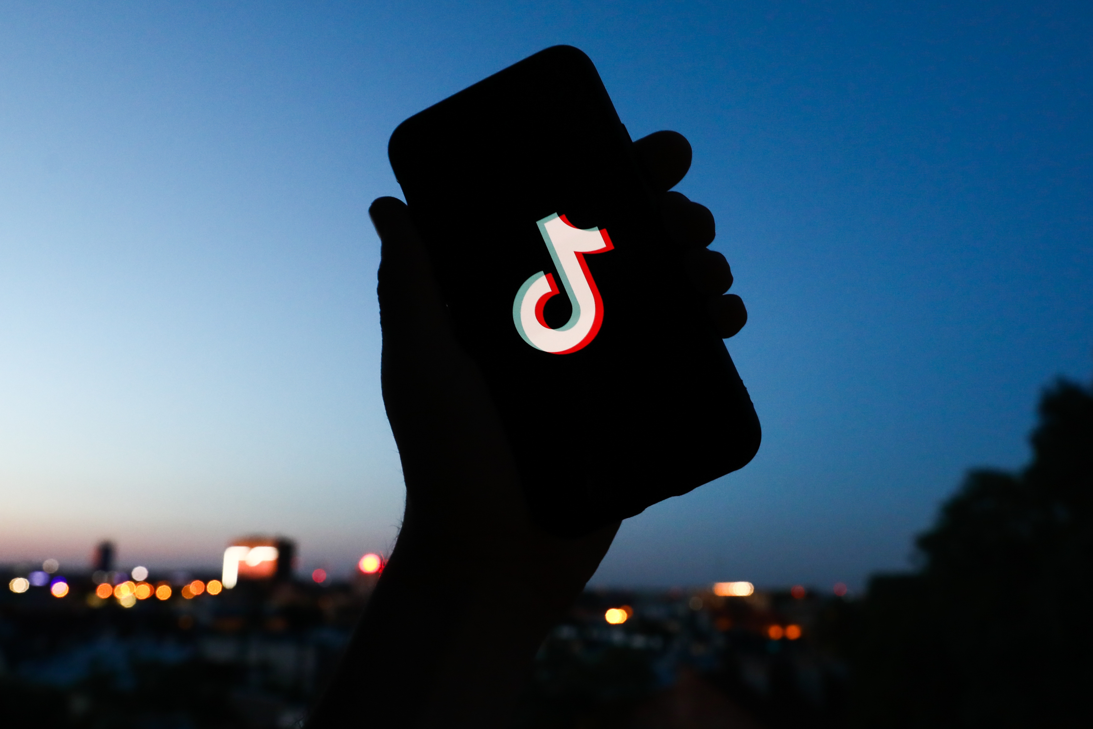 A hand holding up a phone with the TikTok logo on it.