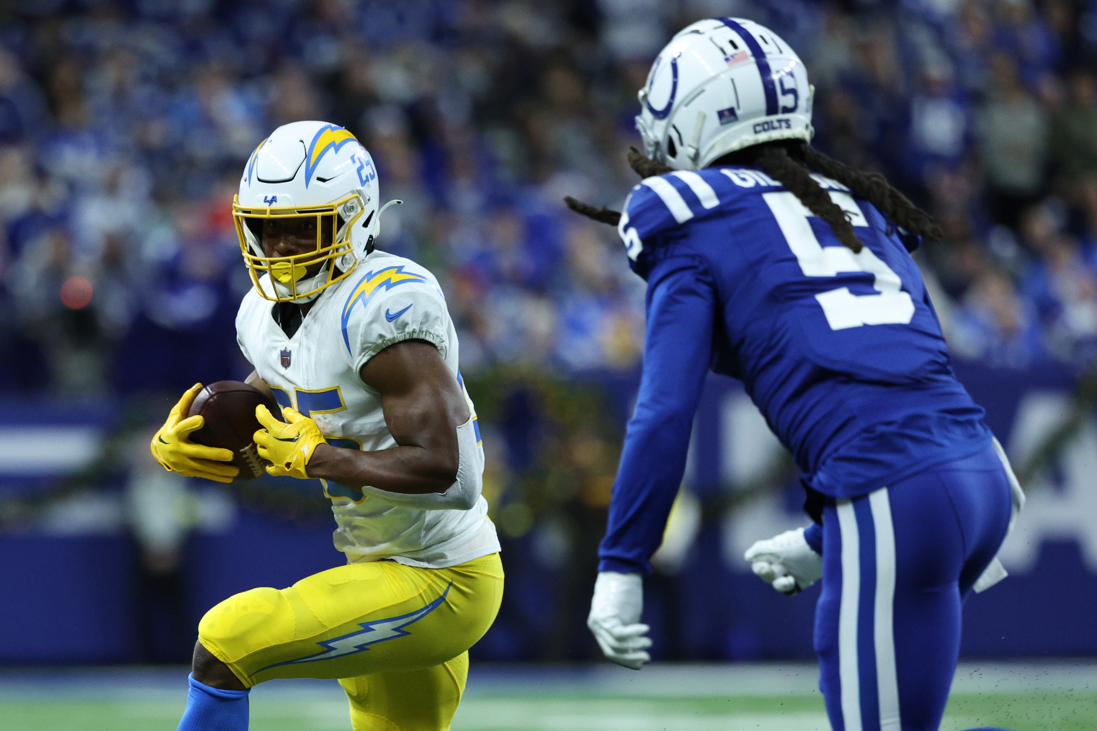 Joshua Kelley #25 of the Los Angeles Chargers runs with the ball against Stephon Gilmore #5 of the Indianapolis Colts at Lucas Oil Stadium on December 26, 2022 in Indianapolis, Indiana.
