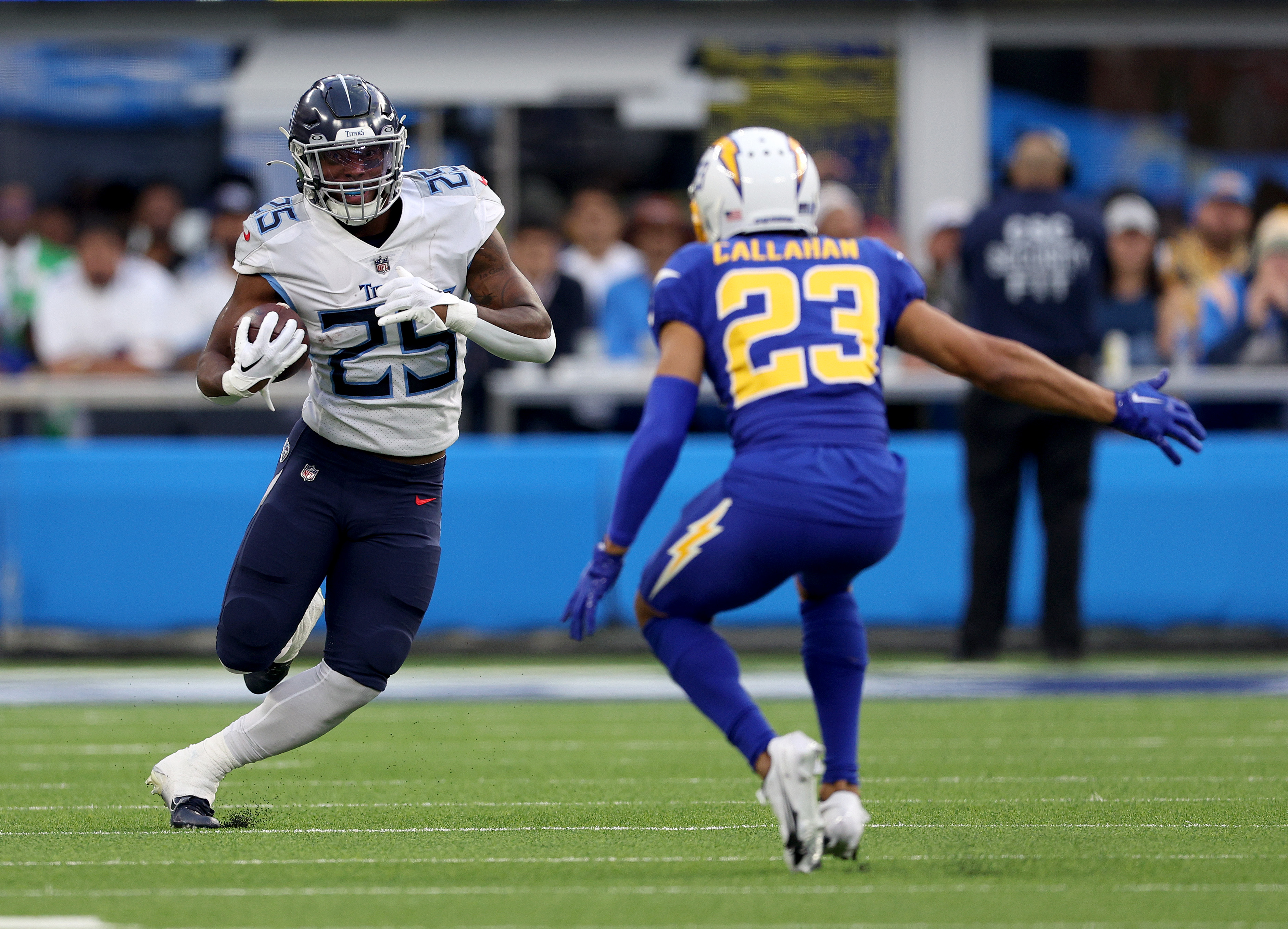 Hassan Haskins #25 of the Tennessee Titans runs with the ball in front of Bryce Callahan #23 of the Los Angeles ChargBryce Callahan #23 of the Los Angeles Chargersduring a 17-14 loss to the Chargers at SoFi Stadium on December 18, 2022 in Inglewood, California.