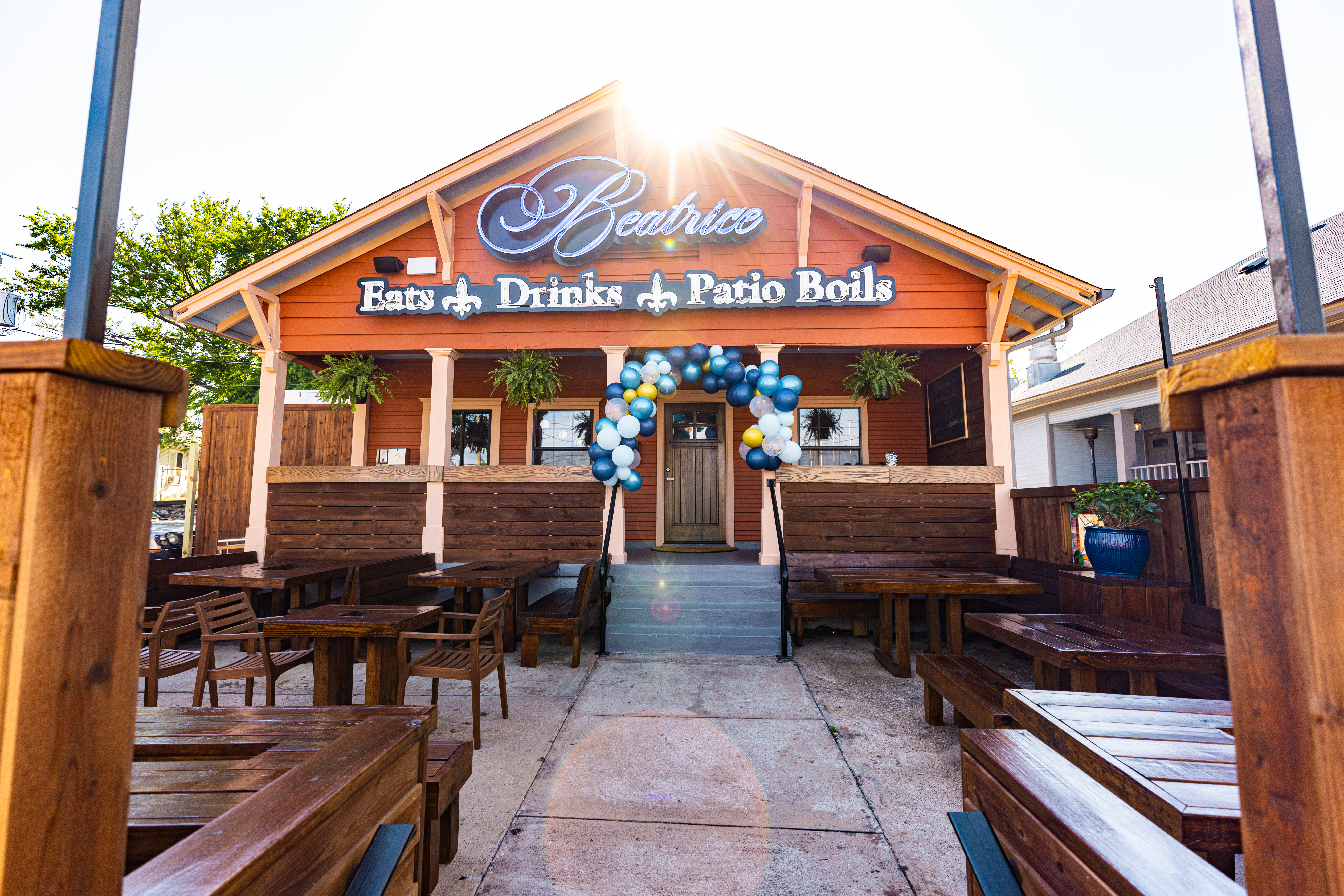 The orange clapboard exterior of Restaurant Beatrice looks like a refurbished home. The sign is white with blue outline and reads: Beatrice. Eats. Drinks. Patio Boils.