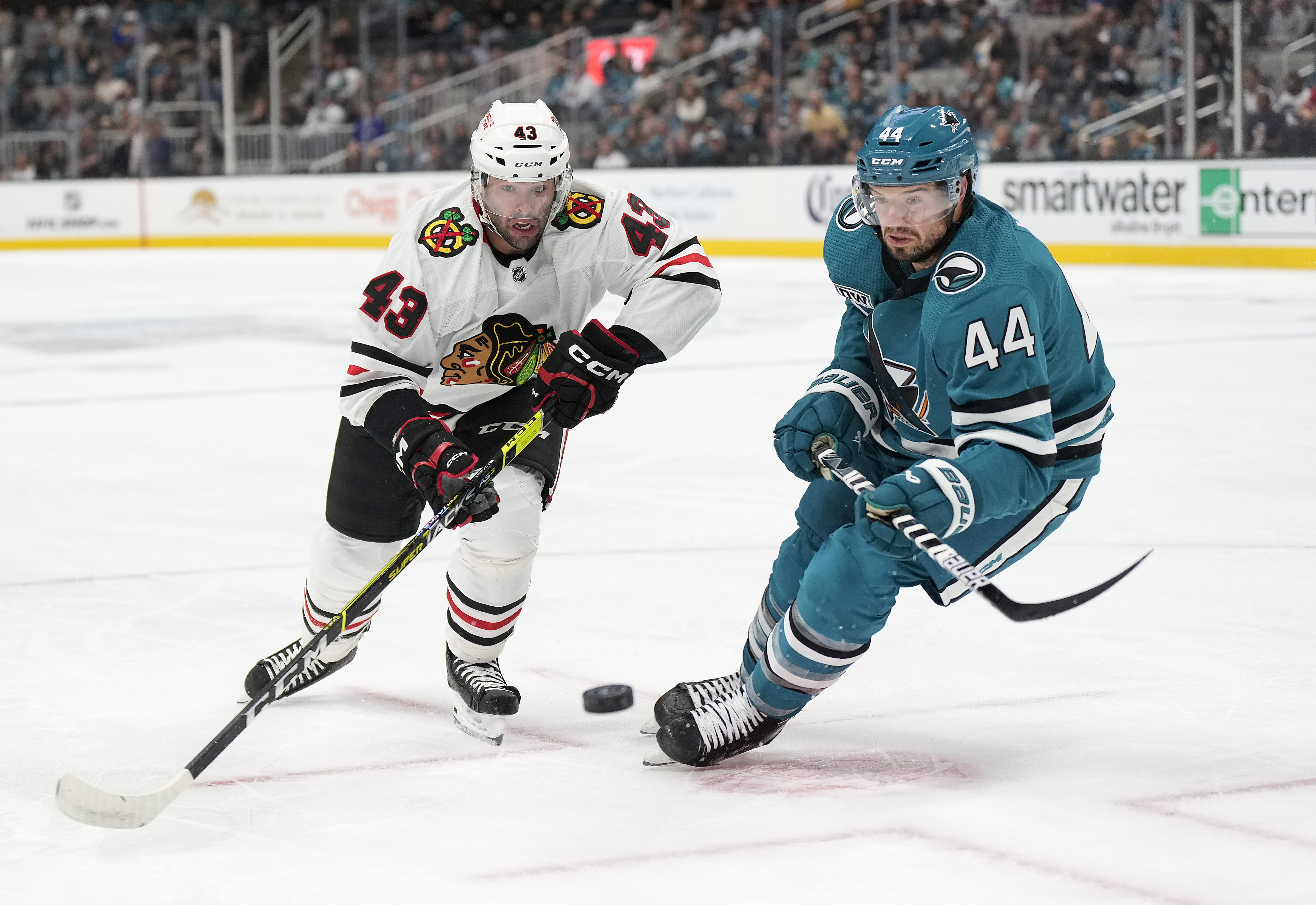 Colin Blackwell #43 of the Chicago Blackhawks and Marc-Edouard Vlasic #44 of the San Jose Sharks races to gain control of the puck during the first period of an NHL Hockey game at SAP Center on October 15, 2022 in San Jose, California.