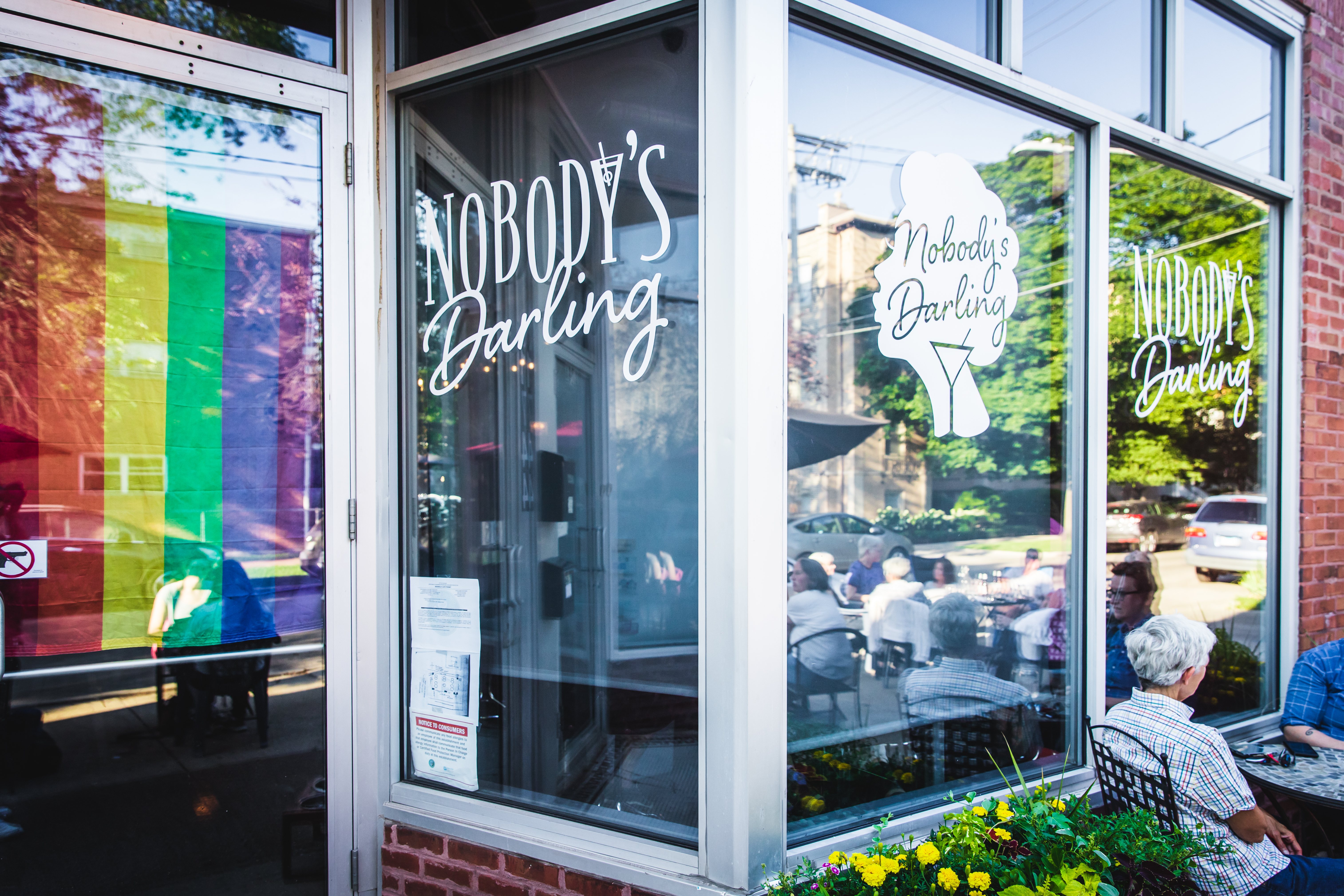 A bar entrance from the outside with signs that read “Nobody’s Darling.”