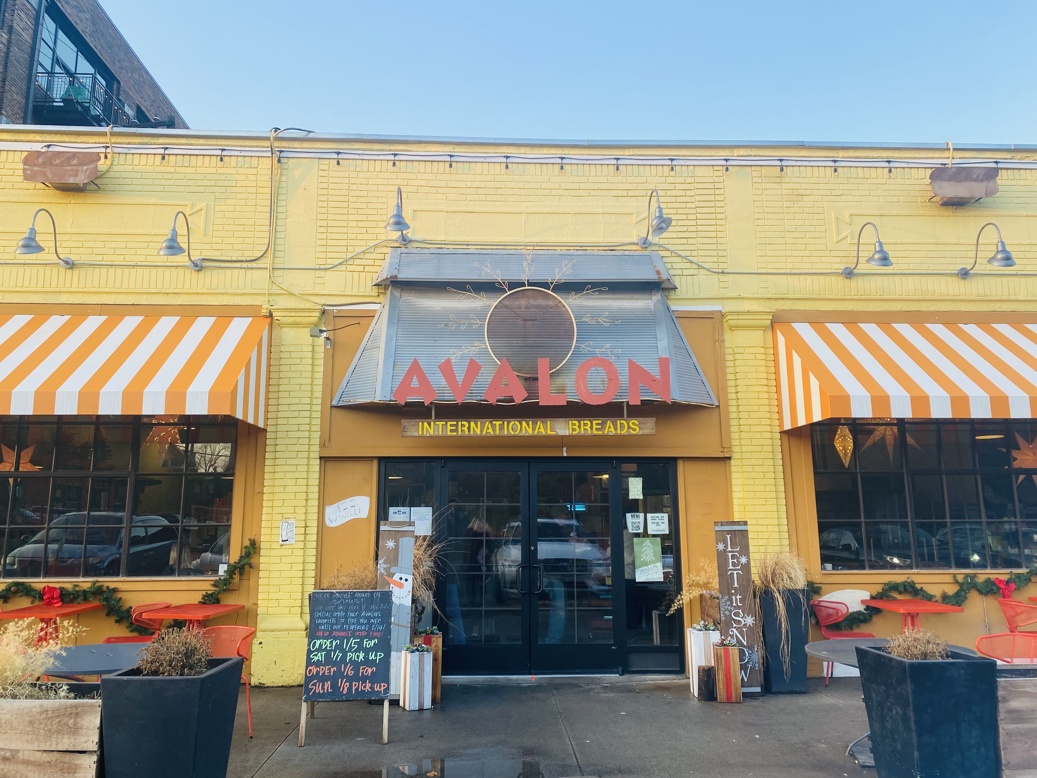 Avalon Bakery in Midtown, Detroit is a brick, single-story building painted yellow with orange and white awnings, and limited orange-colored seating and tables.