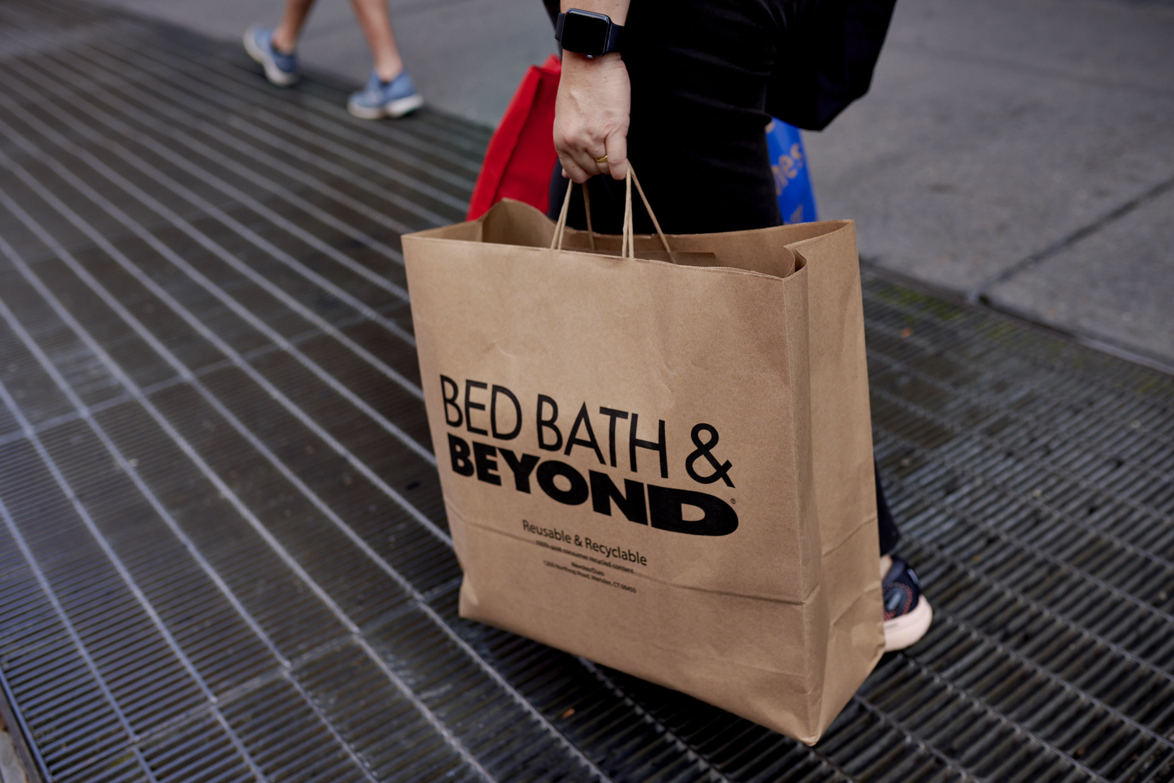 A person carrying a Bed Bath &amp; Beyond bag.