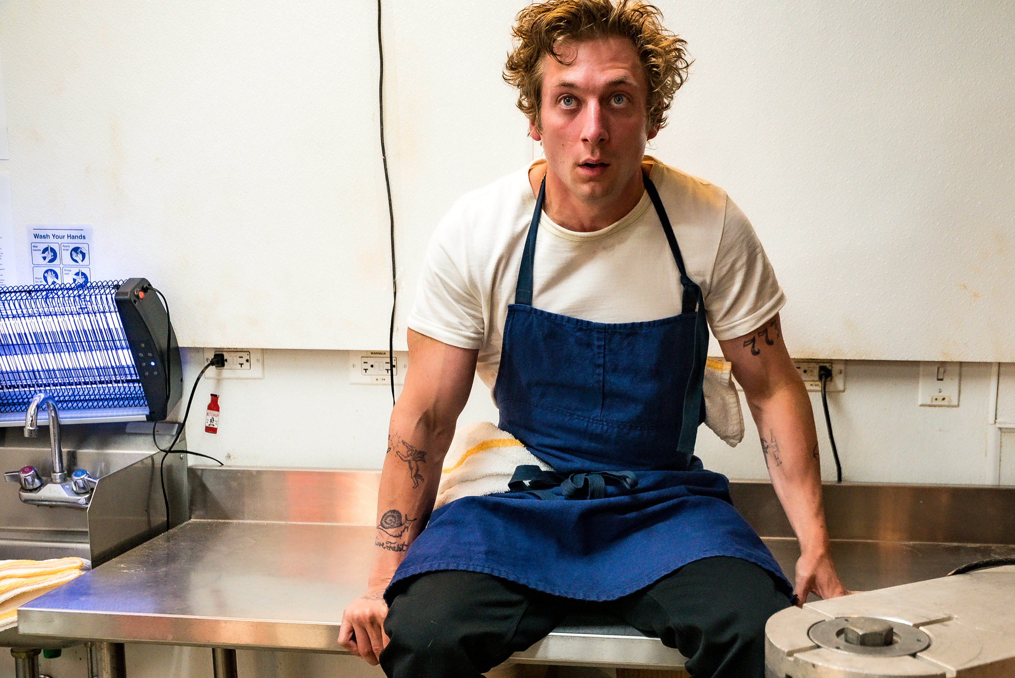 Jeremy Allen White as Carmen ‘Carmy’ Berzatto sitting on a kitchen counter 