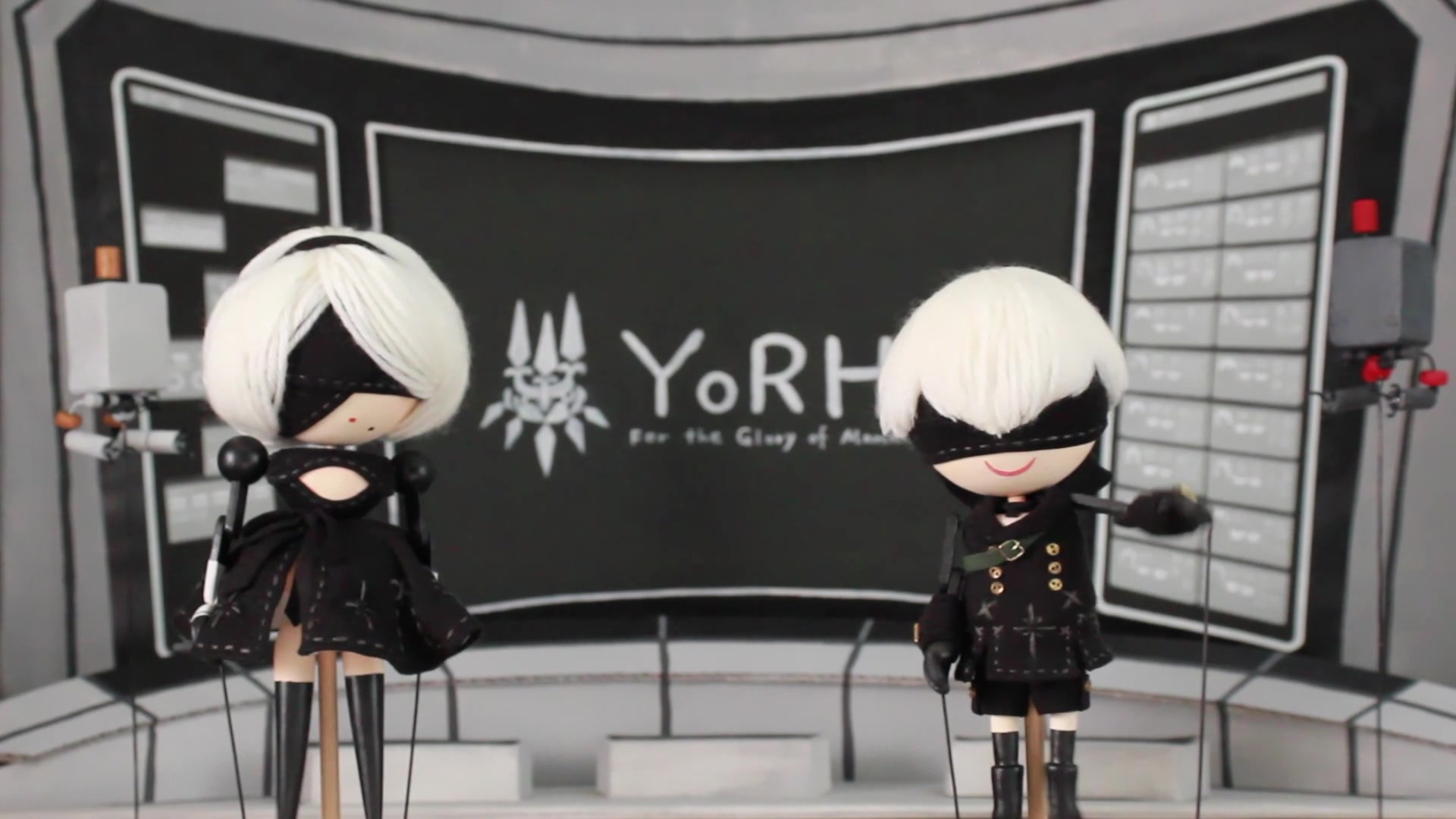 Puppets of Nier Automata protagonists 2B and 9S stand in a classroom